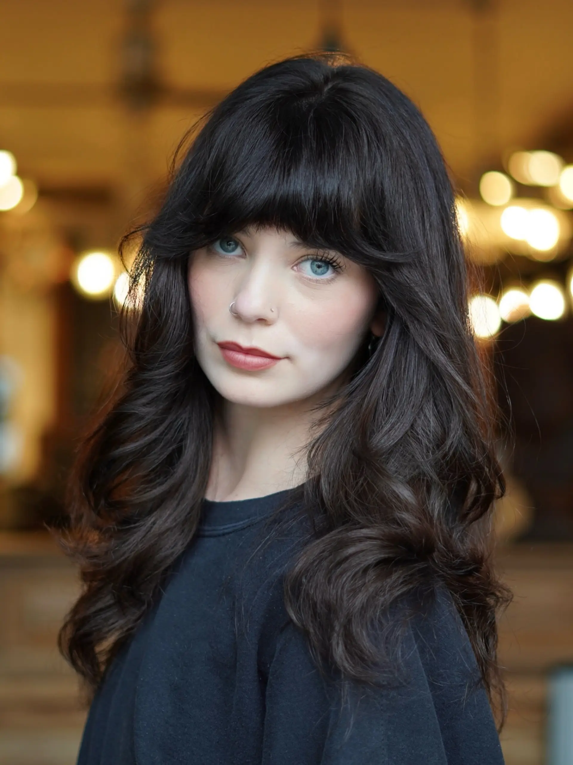 A retro-inspired modern shag cut on long, rich dark brunette hair, styled with textured bangs, feathered curtain layers, and voluminous waves. 1
