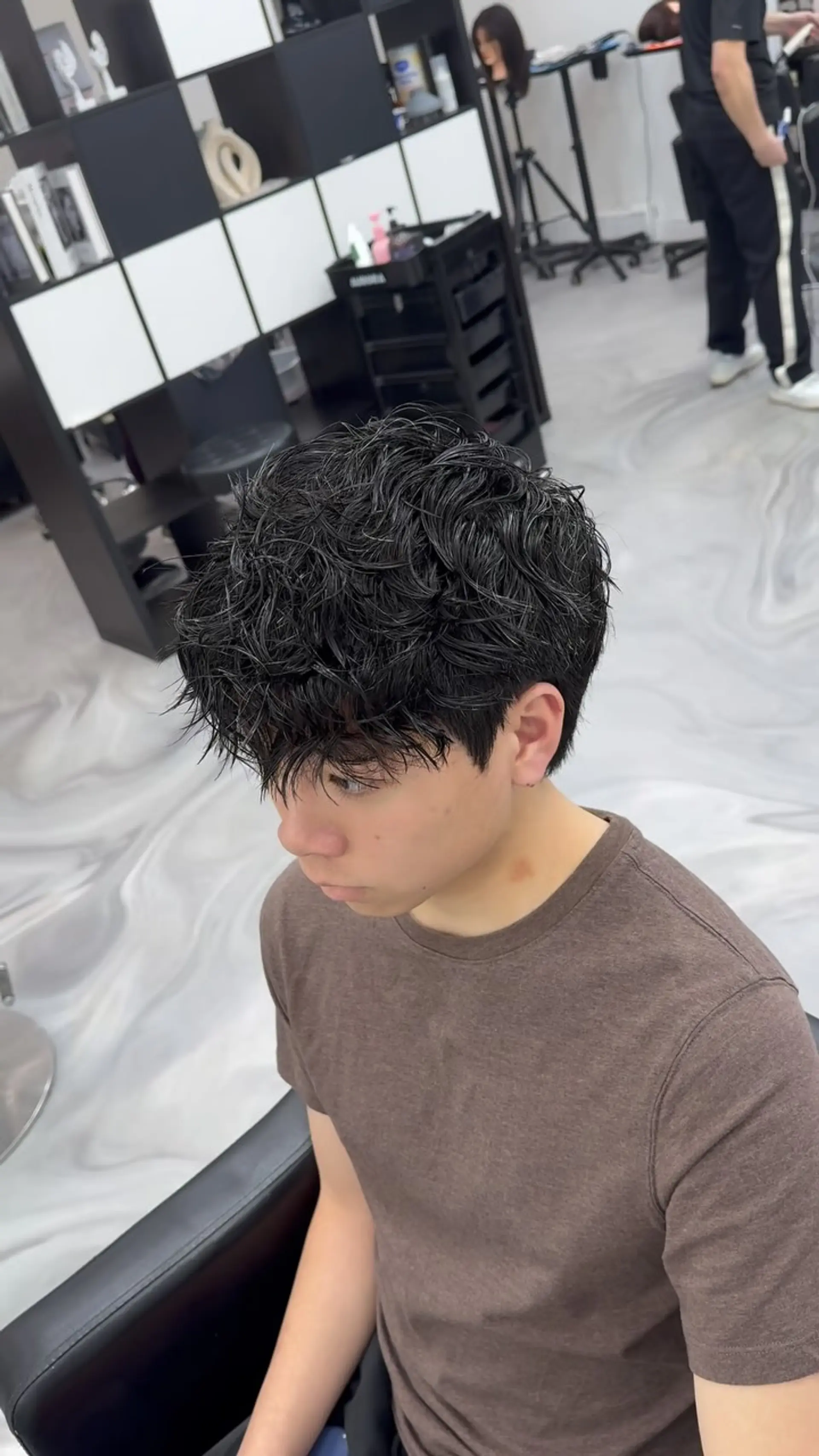 A short, heavily textured haircut featuring piecey, defined curls styled forward with a wet finish. 1
