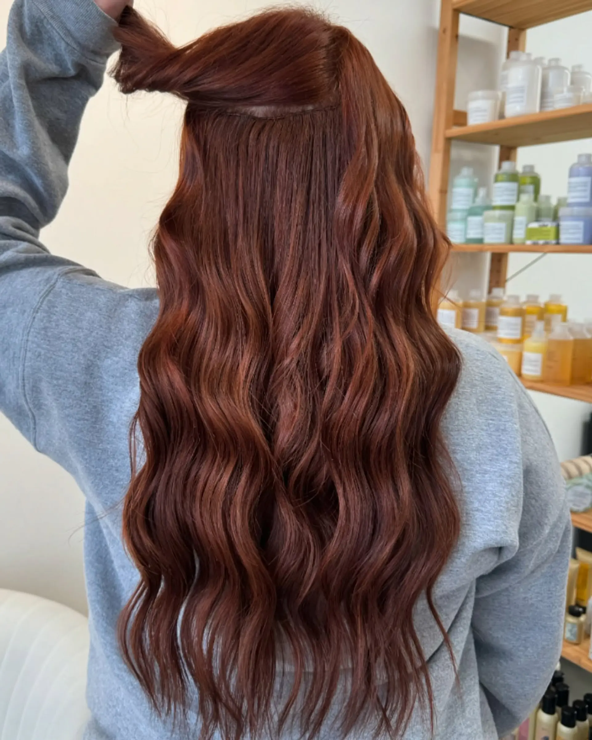 Long dark copper hair styled into loose, flowing waves with hand-tied extensions. 1