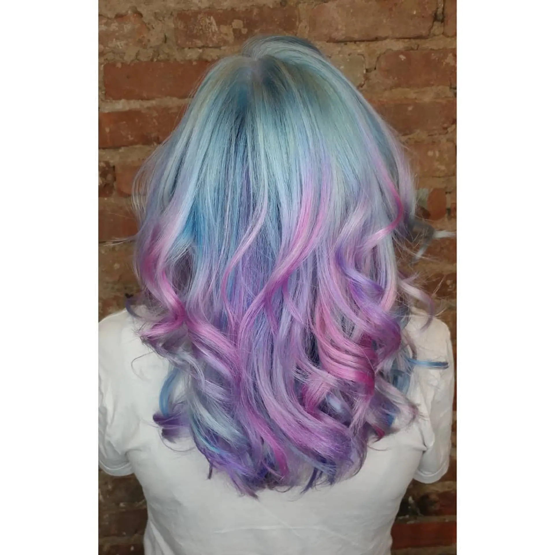 Medium-length pastel multi-toned hair featuring shades of icy blue, lavender, and pink styled into loose, bouncy curls. 1