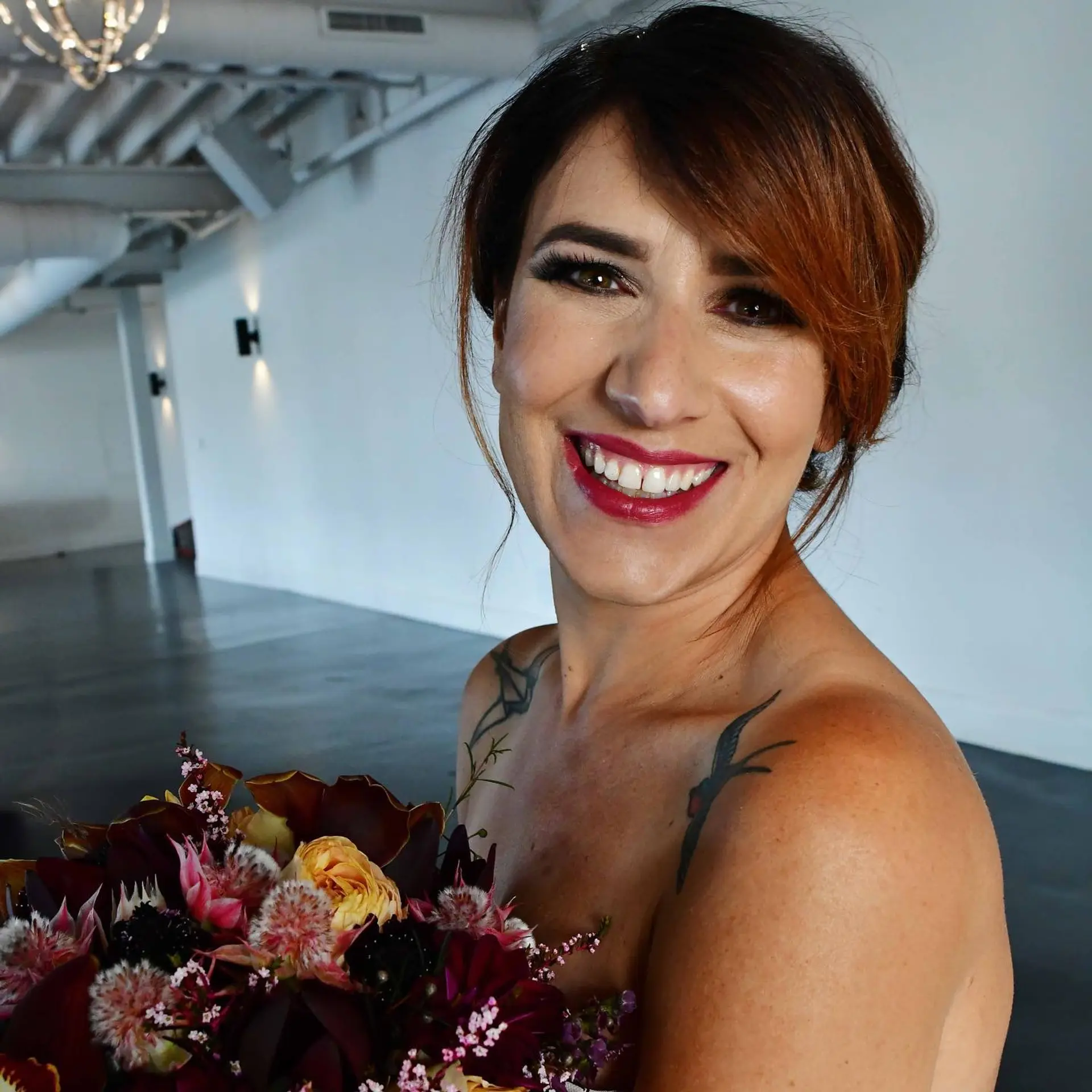 A sophisticated bridal updo styled with smooth, side-swept fringe framing the face. 1