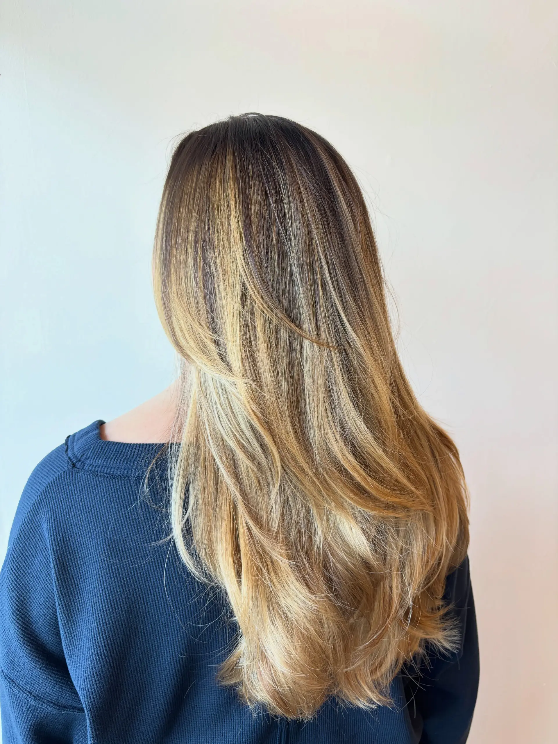 Long hair featuring a seamless warm golden blonde balayage blend and soft cascading layers. 1