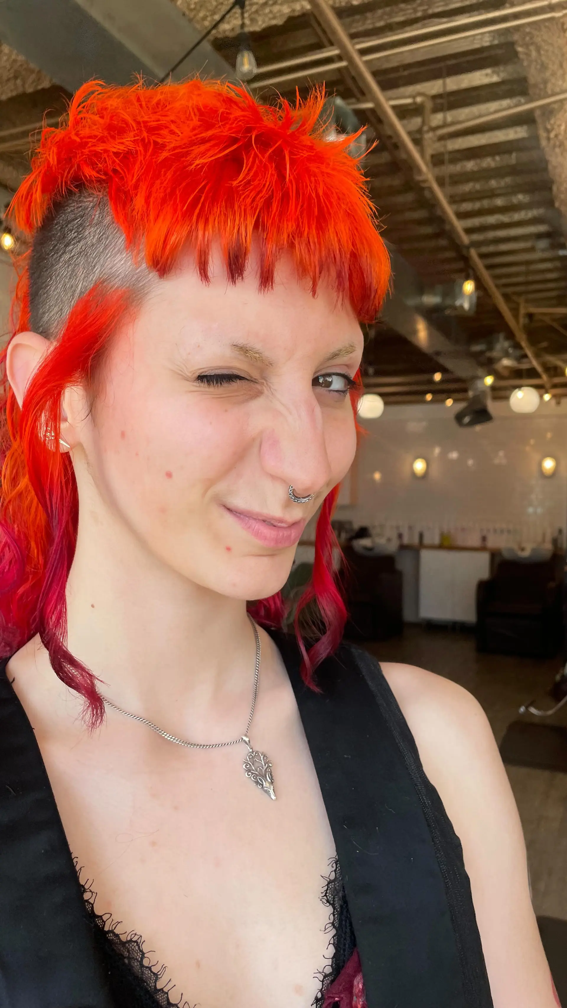 A bold vivid orange mullet featuring shaved undercut sides, textured choppy micro bangs, and longer wavy pieces trailing down the neck. 1