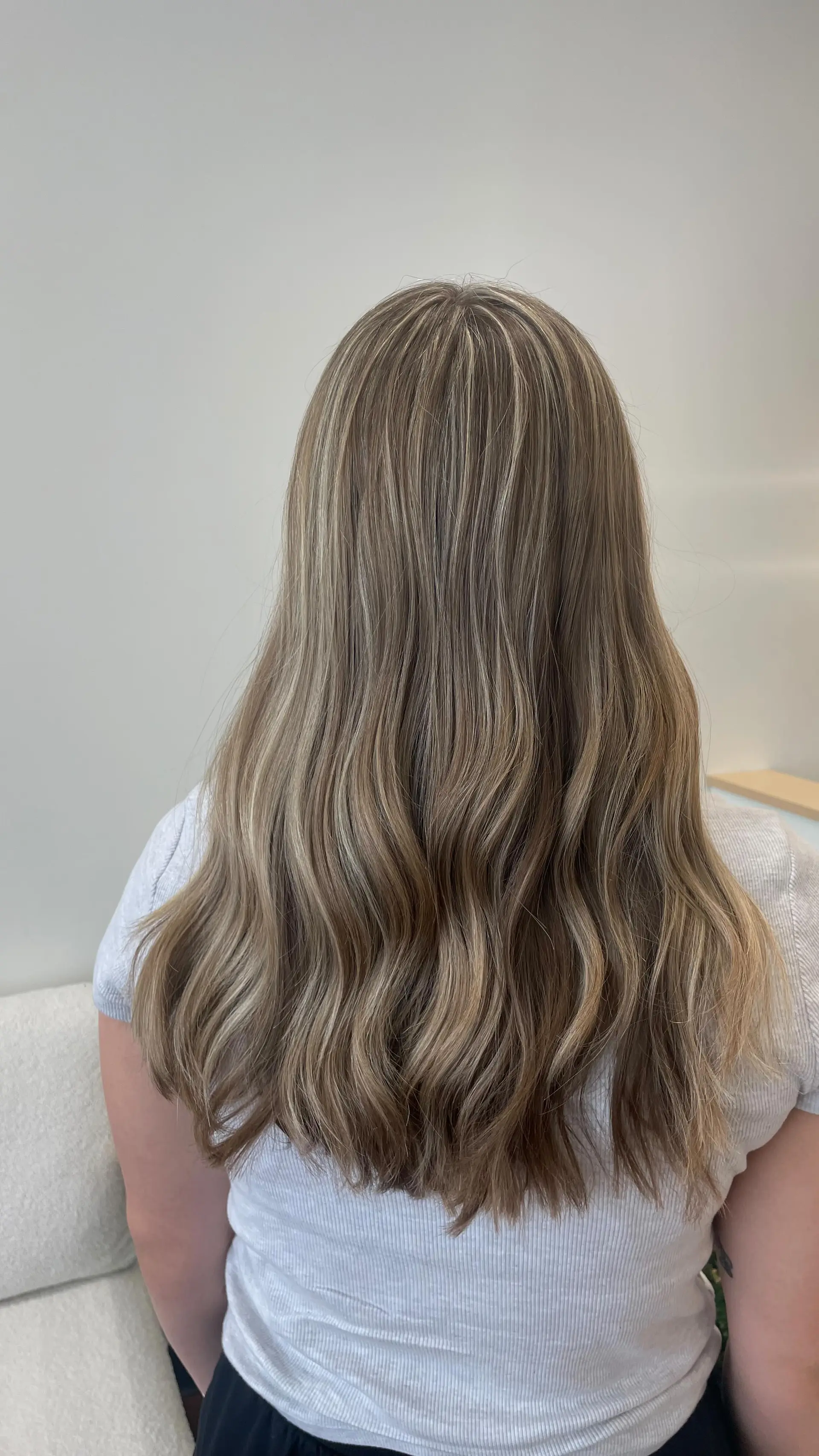 Long hair featuring dimensional cool blonde highlights woven through a natural light brown base, finished with soft, relaxed waves. 1