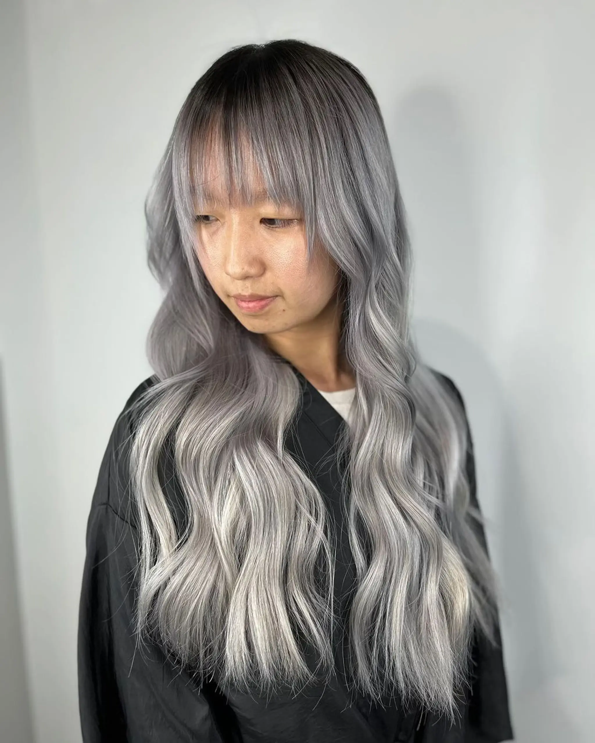 A very long wavy hairstyle with an ombre transition from platinum to silver, featuring face-framing bangs and layered ends.
Stylist - @xcellent_jason