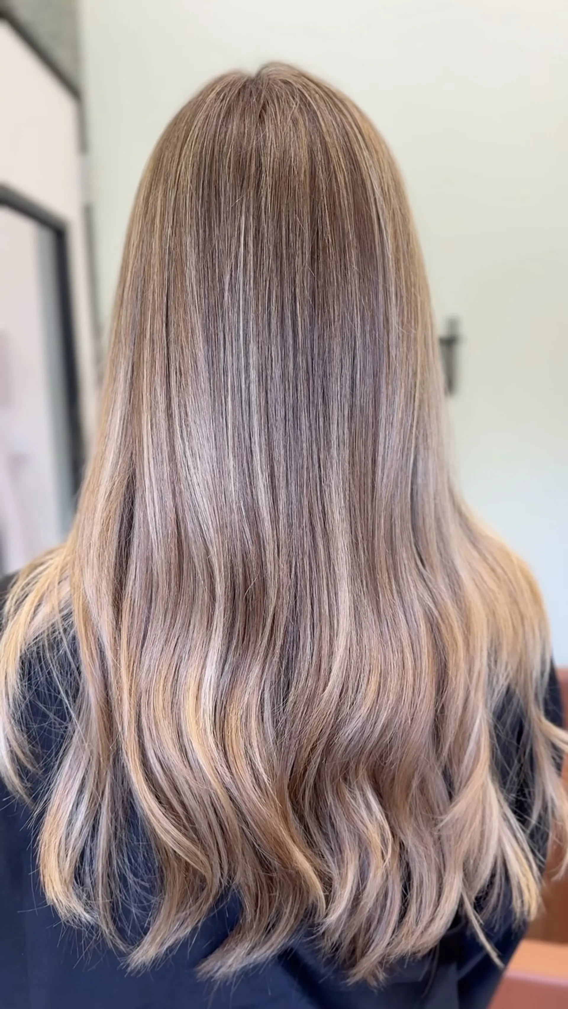 Long hair featuring a multi-dimensional ash and beige blonde balayage with seamless blending and soft waves at the ends. 1