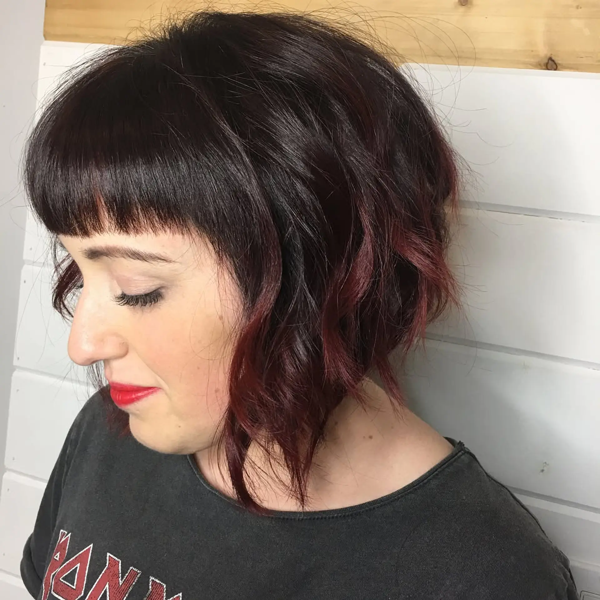 A textured A-line bob with blunt micro bangs and soft, lived-in waves, accented with deep burgundy tones at the ends. 1