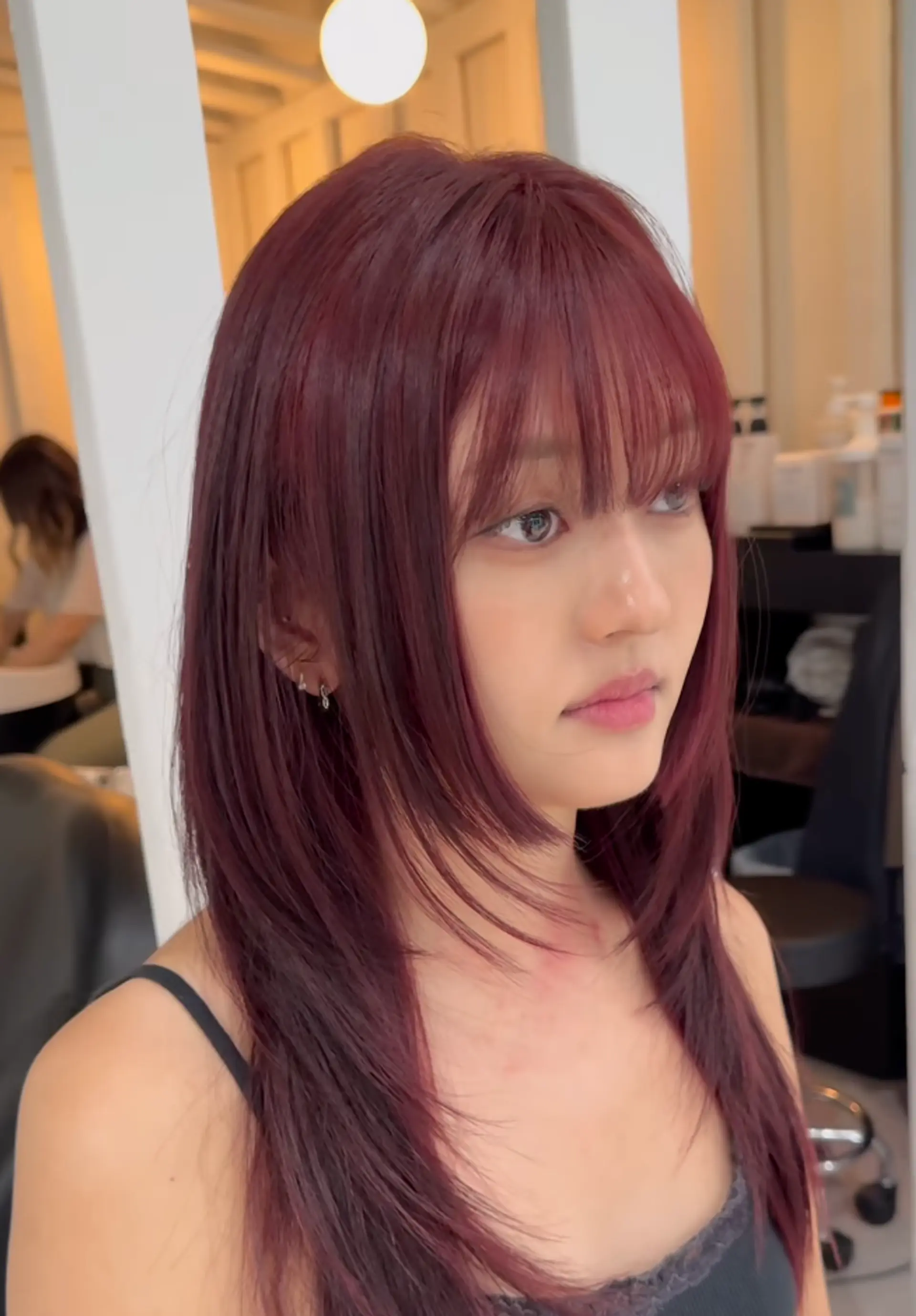 Long, straight hair in burgundy and maroon, with side-swept layers, a full fringe, and a glossy finish. 1
