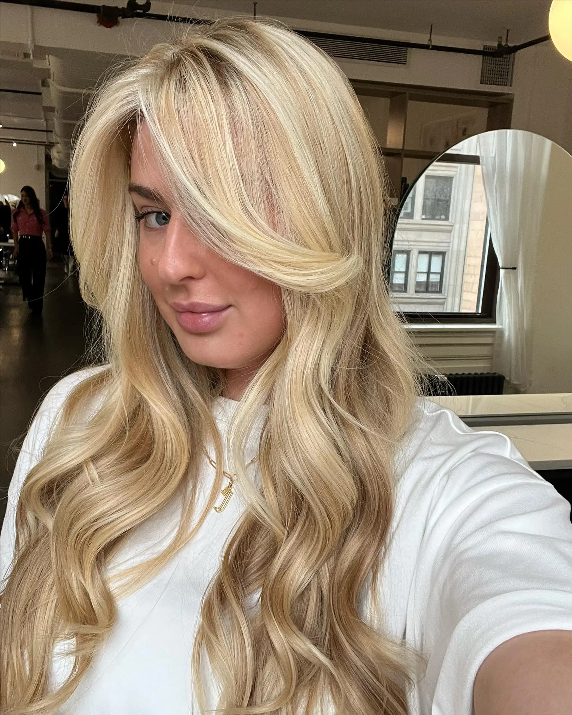 Long multi-tonal blonde hair styled in soft voluminous waves with sweeping face-framing fringe. 1