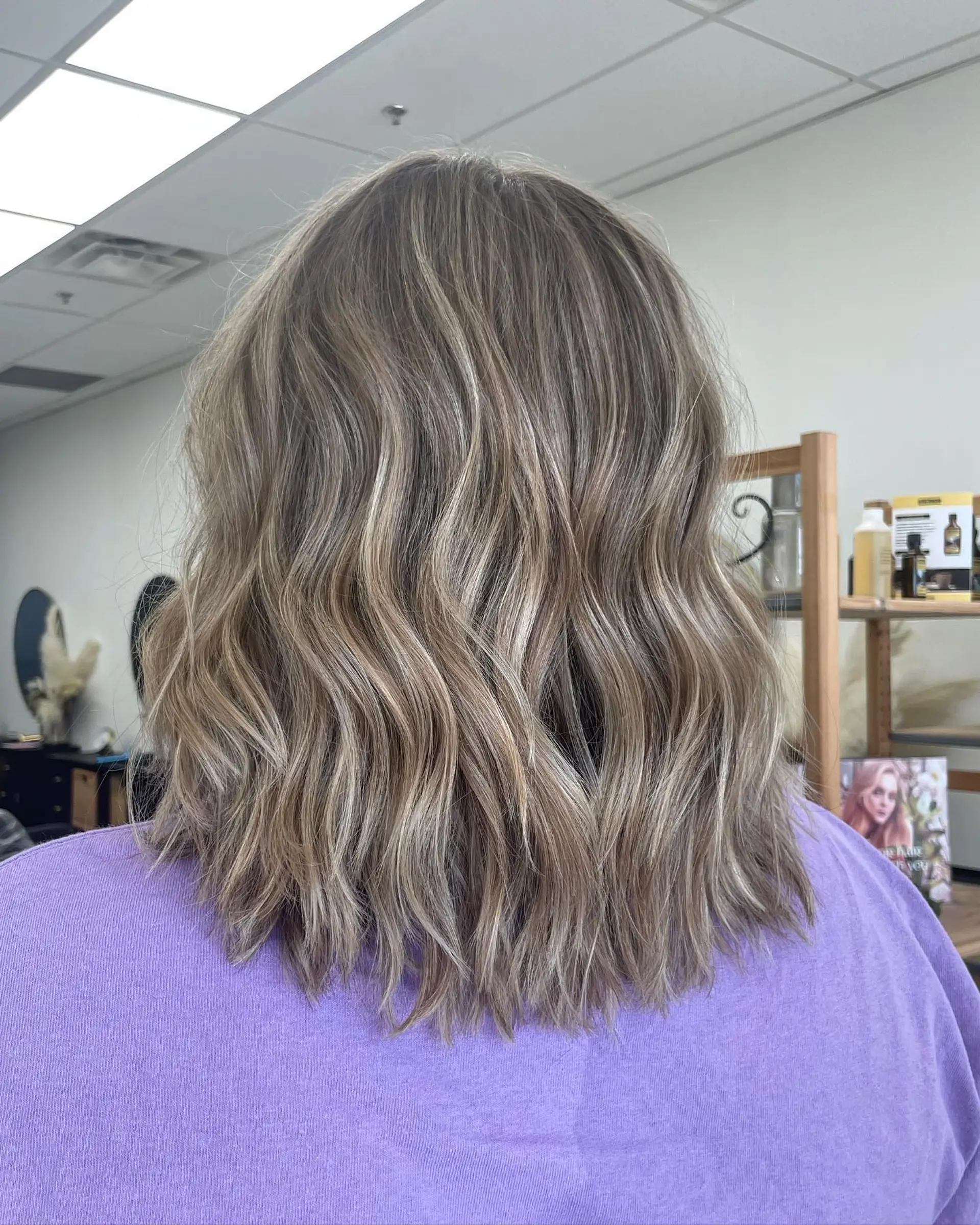 Shoulder-length textured lob with blended cool ash blonde babylights styled in soft waves. 1