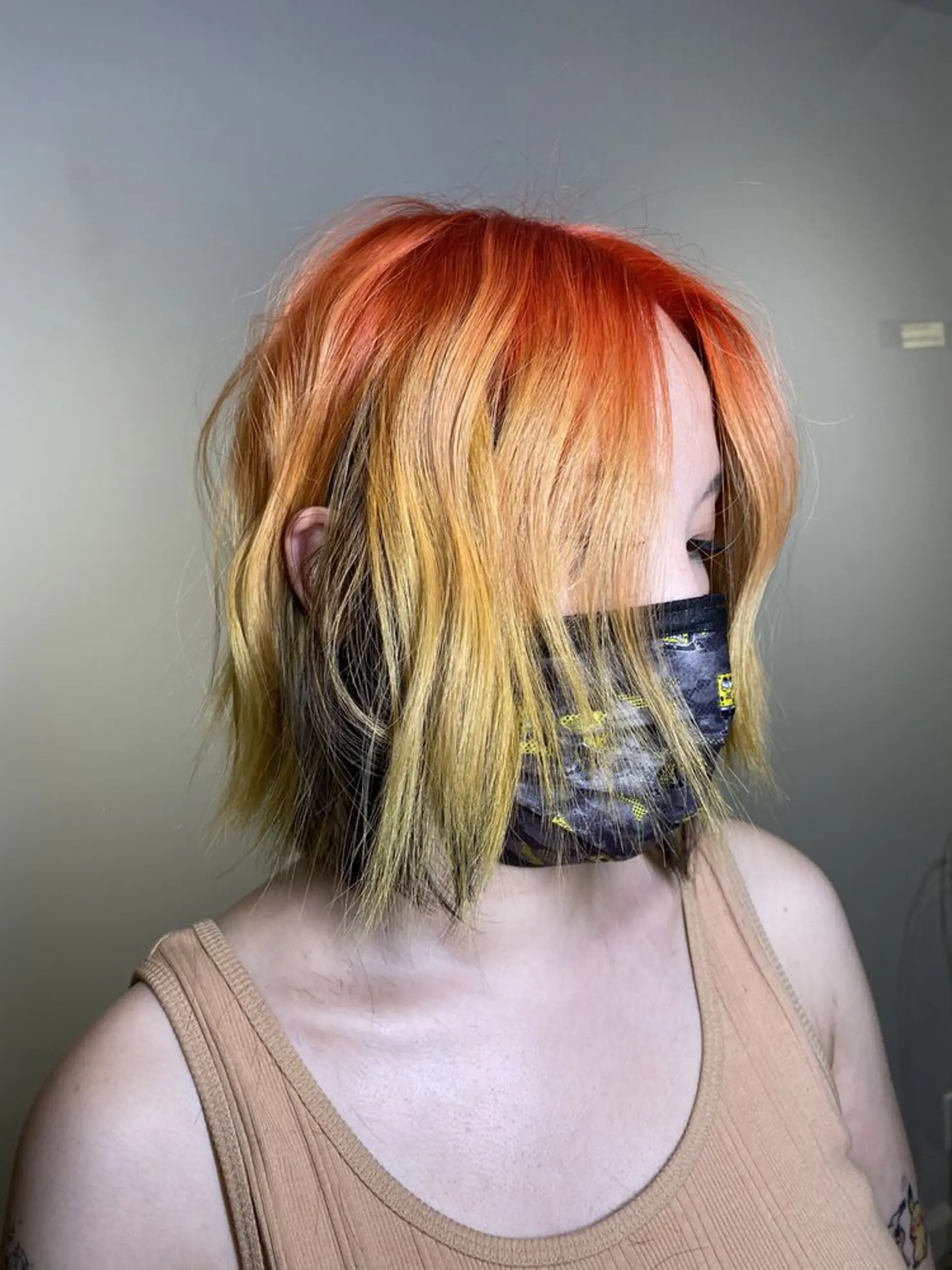 A wavy, short bob with an ombre effect featuring fiery orange roots transitioning to yellow and blonde ends, styled with loose waves. 1