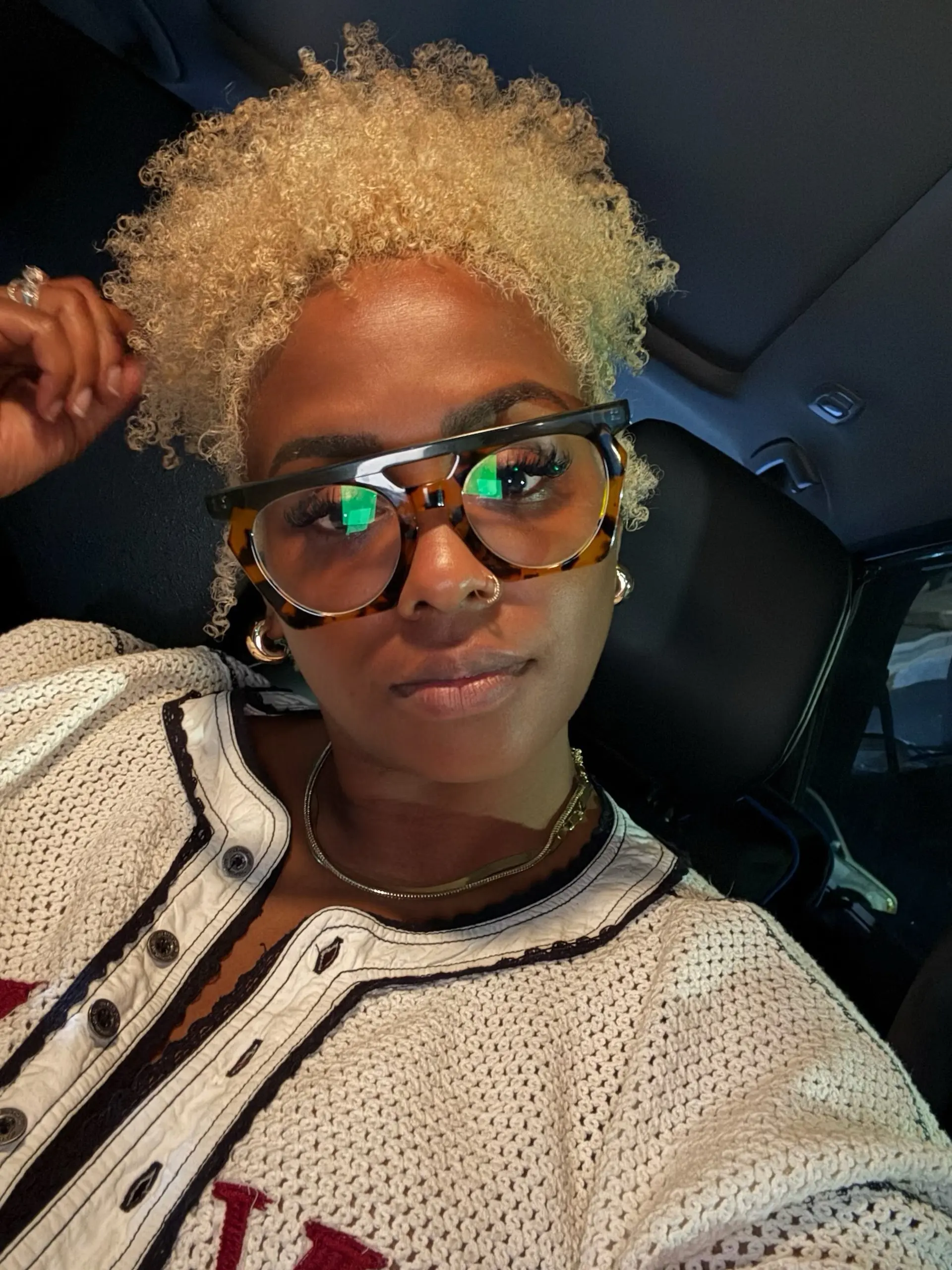 A tapered short curly haircut featuring high-definition natural curls and coils colored in an all-over platinum blonde. 1