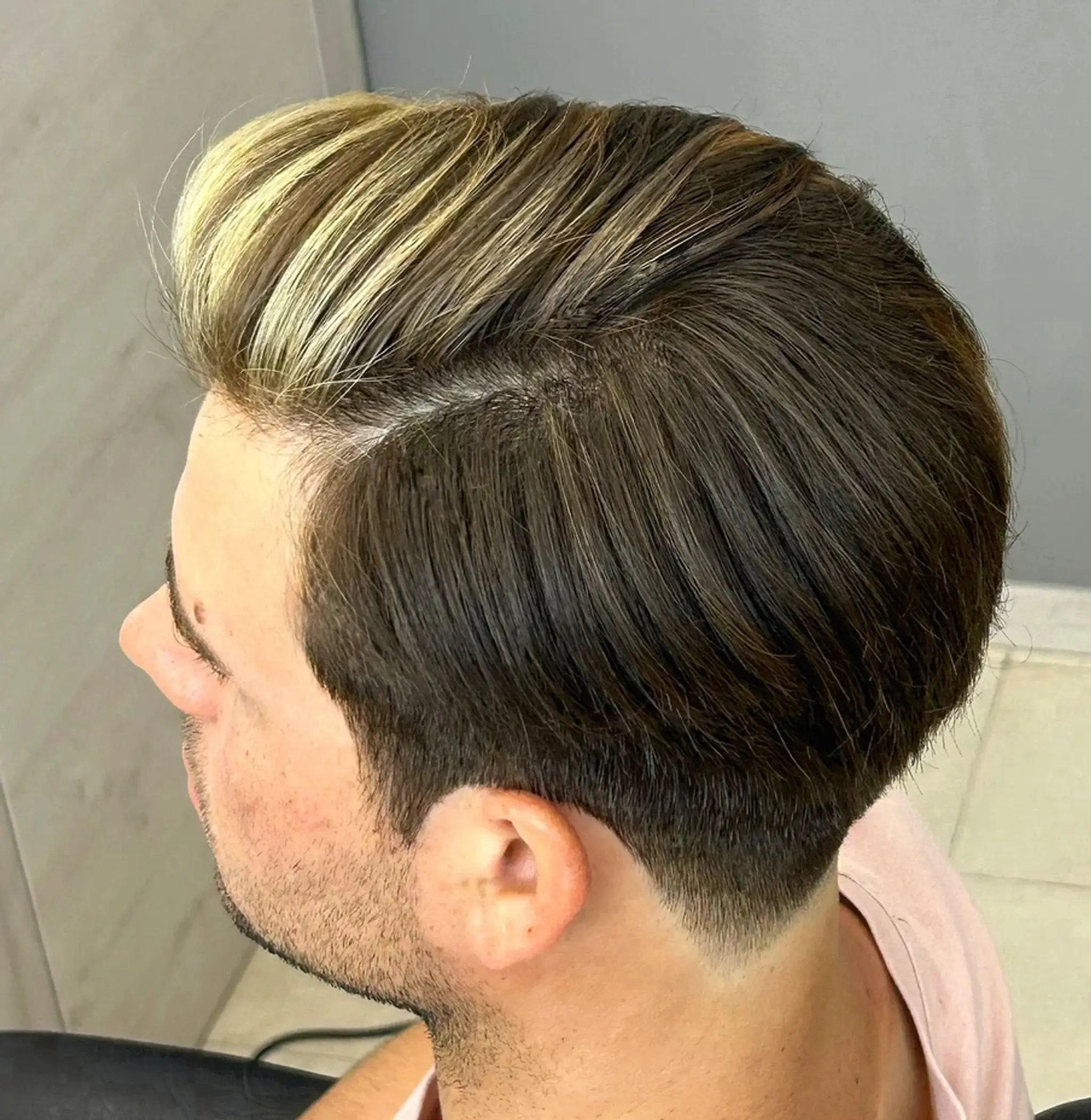 Short straight hair with blonde highlights and a dark brown base, side-parted with a glossy finish and tapered fade.