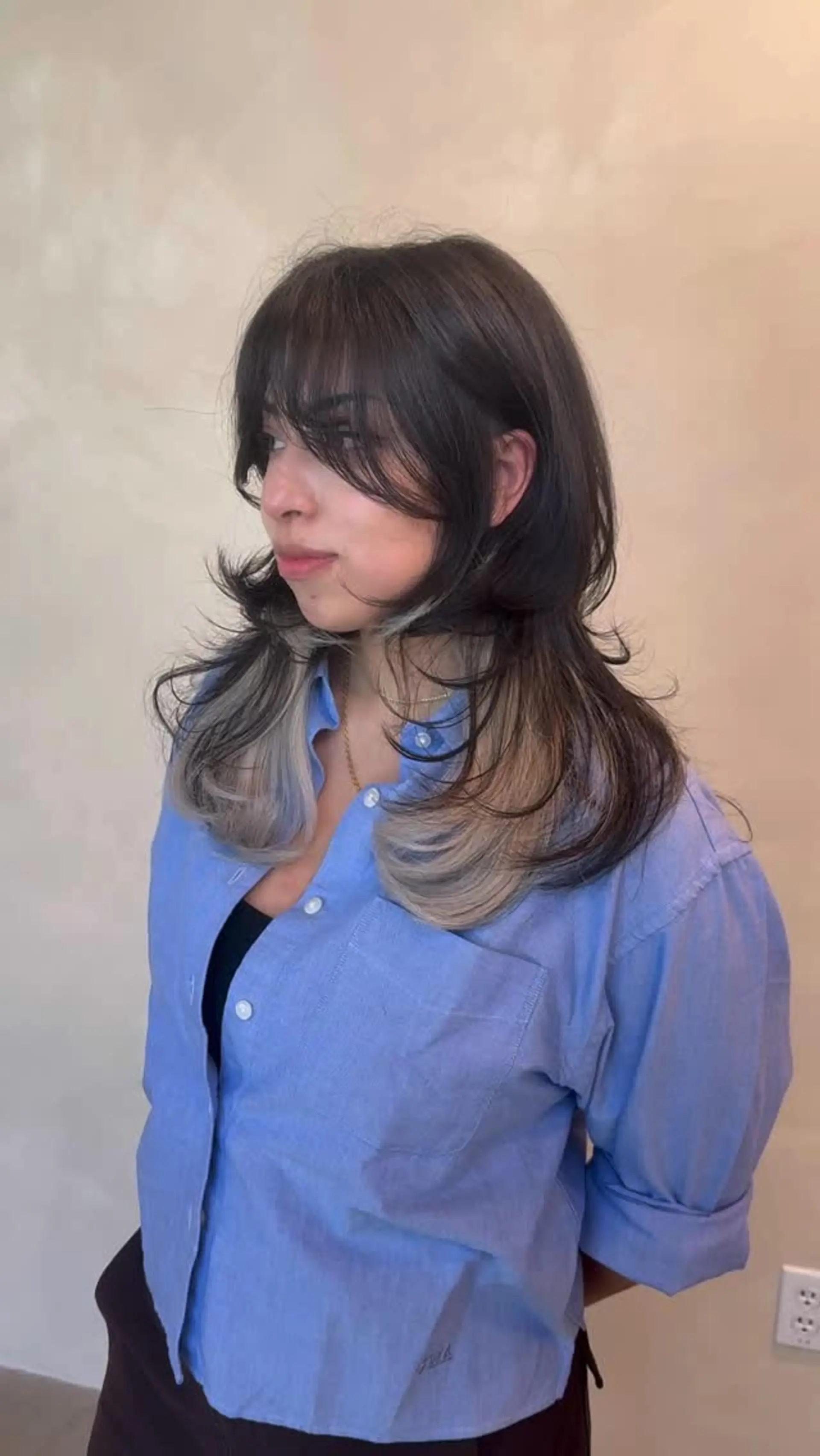 A heavily layered medium-length shag cut featuring wispy bangs, soft face framing, and curled-in ends that reveal peekaboo blonde underneath. 1