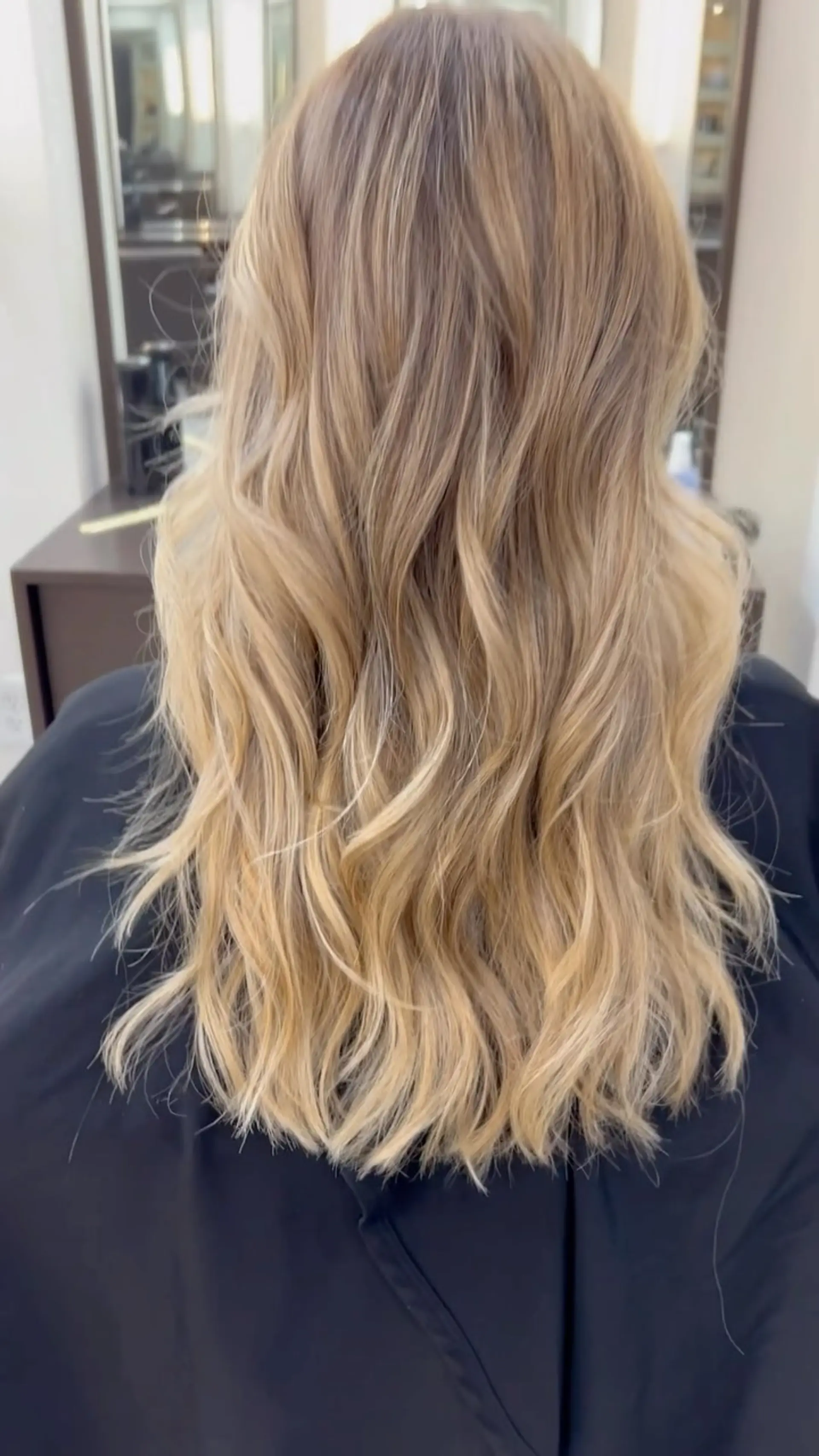 Long hair featuring a seamless blonde balayage styled into soft, tousled waves. 1