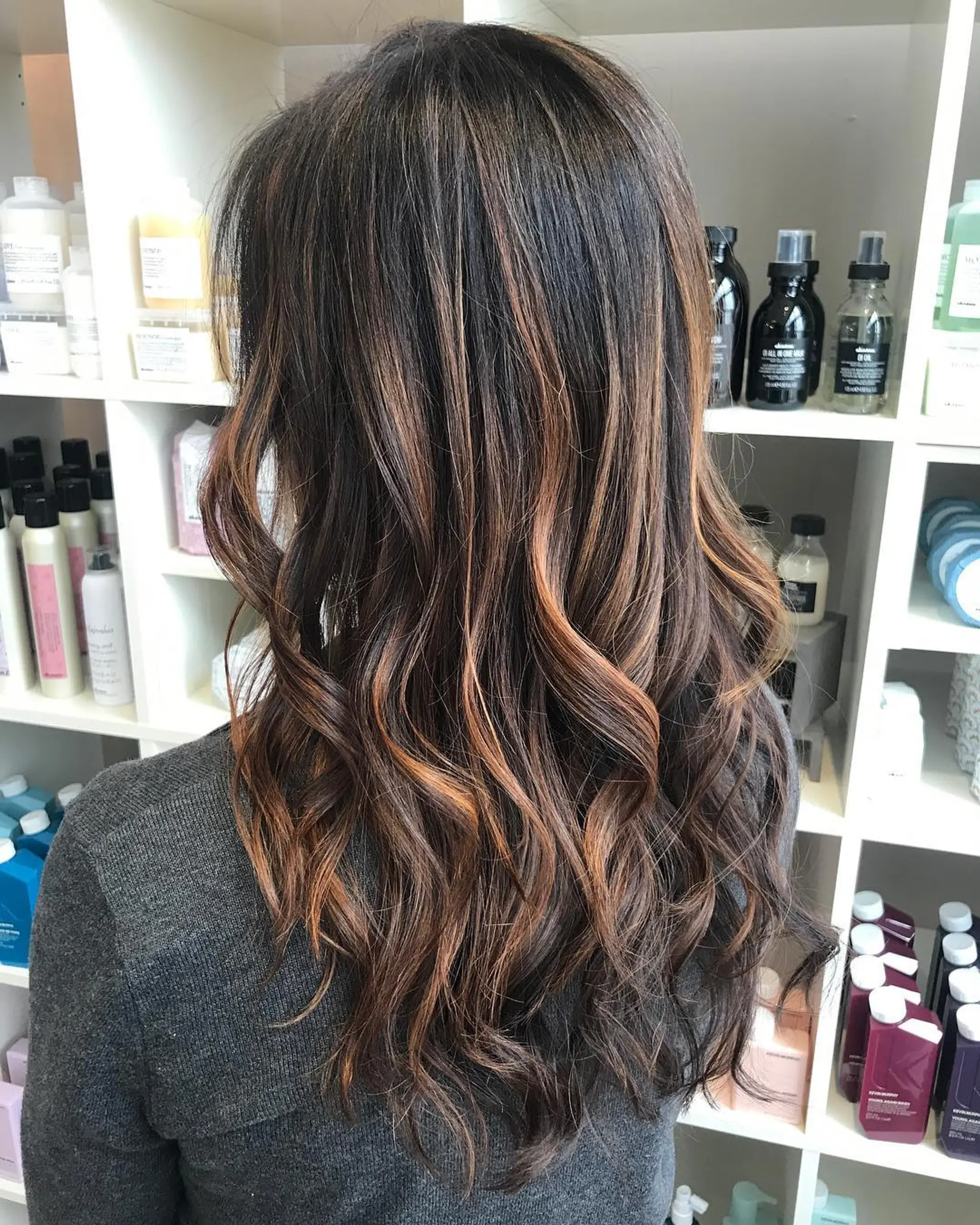 Long dark brunette hair featuring soft caramel balayage highlights styled in loose beach waves. 1