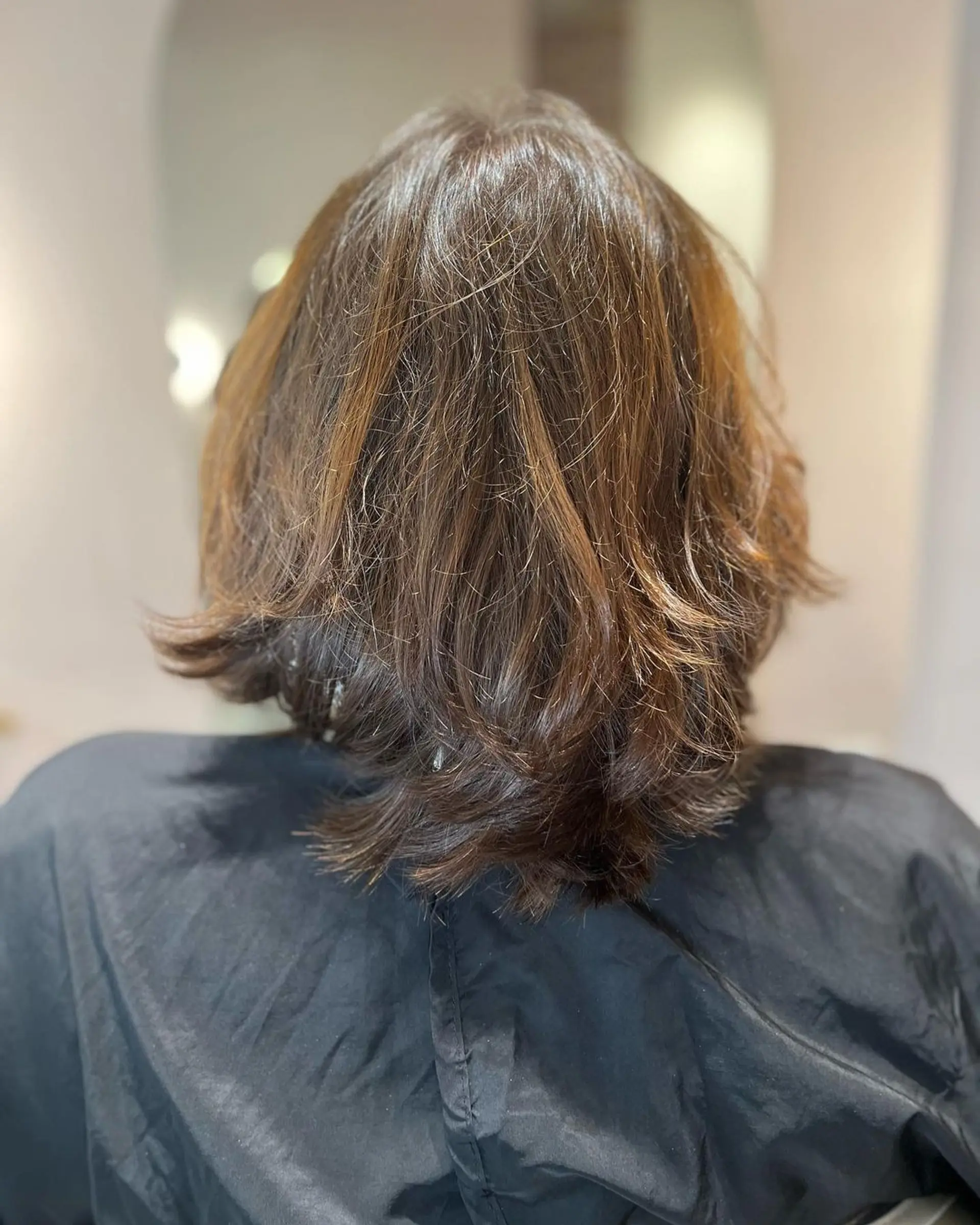 The hairstyle features medium-length straight hair with a natural brown base, accented by undercut pink highlights. Shaggy layers and feathered ends create an edgy look, complemented by a side-swept fringe. 3