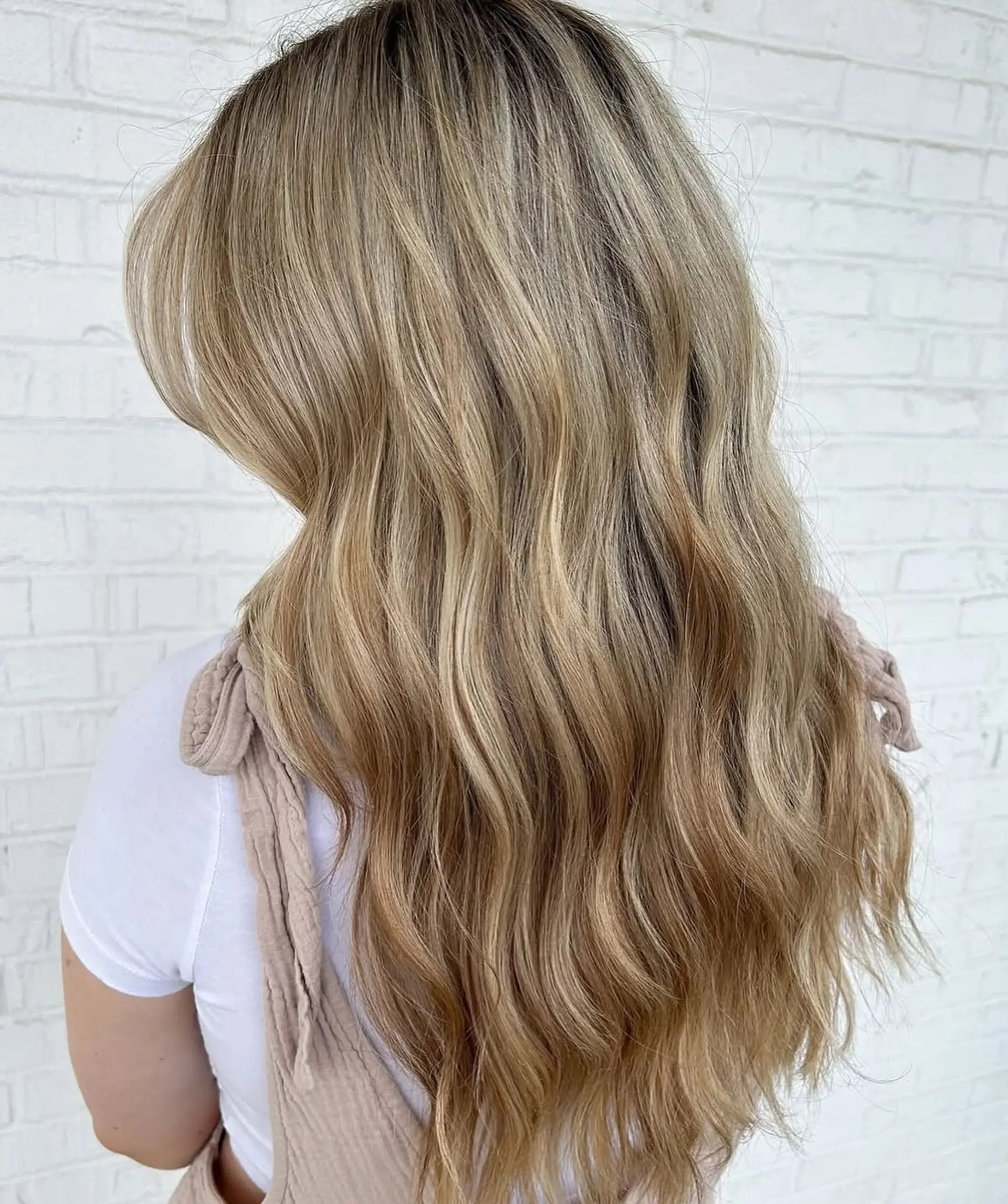 Long hair featuring dimensional warm blonde highlights styled in loose, textured waves. 1