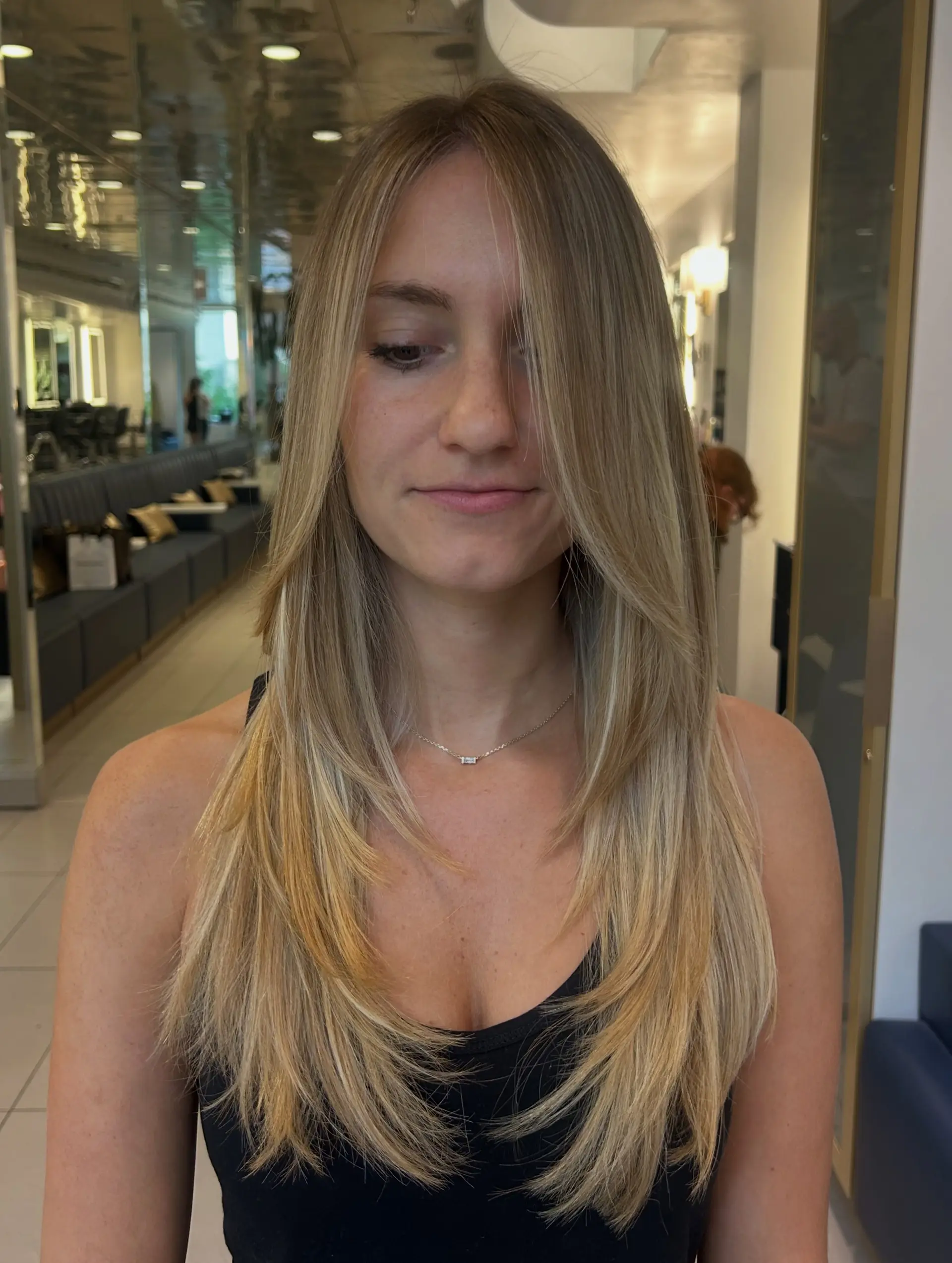 Long blonde hair cut with cascaded face-framing layers and styled in a sleek, curved blowout. 1
