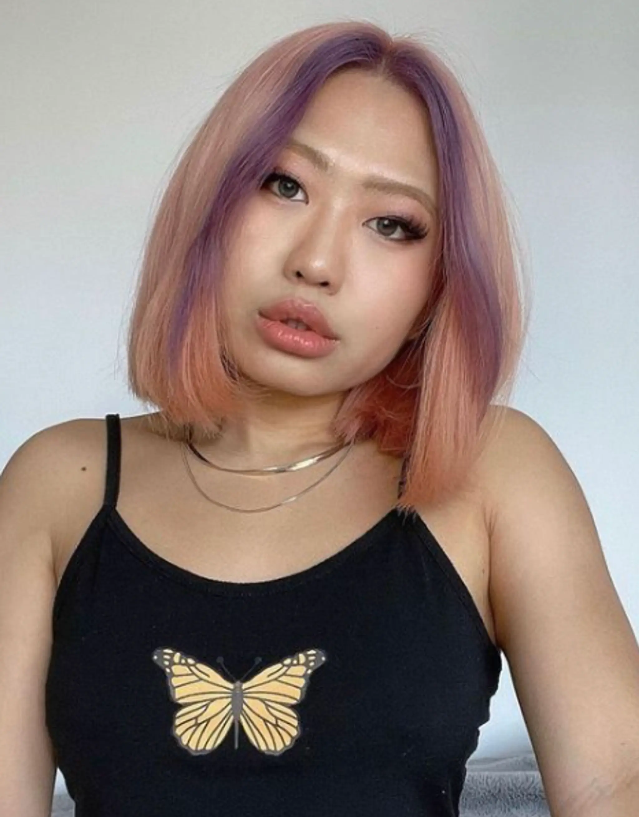 A medium-length straight bob haircut with a peach to purple ombre, creating a serene and playful look with smooth pastel hues and precise face-framing cut.