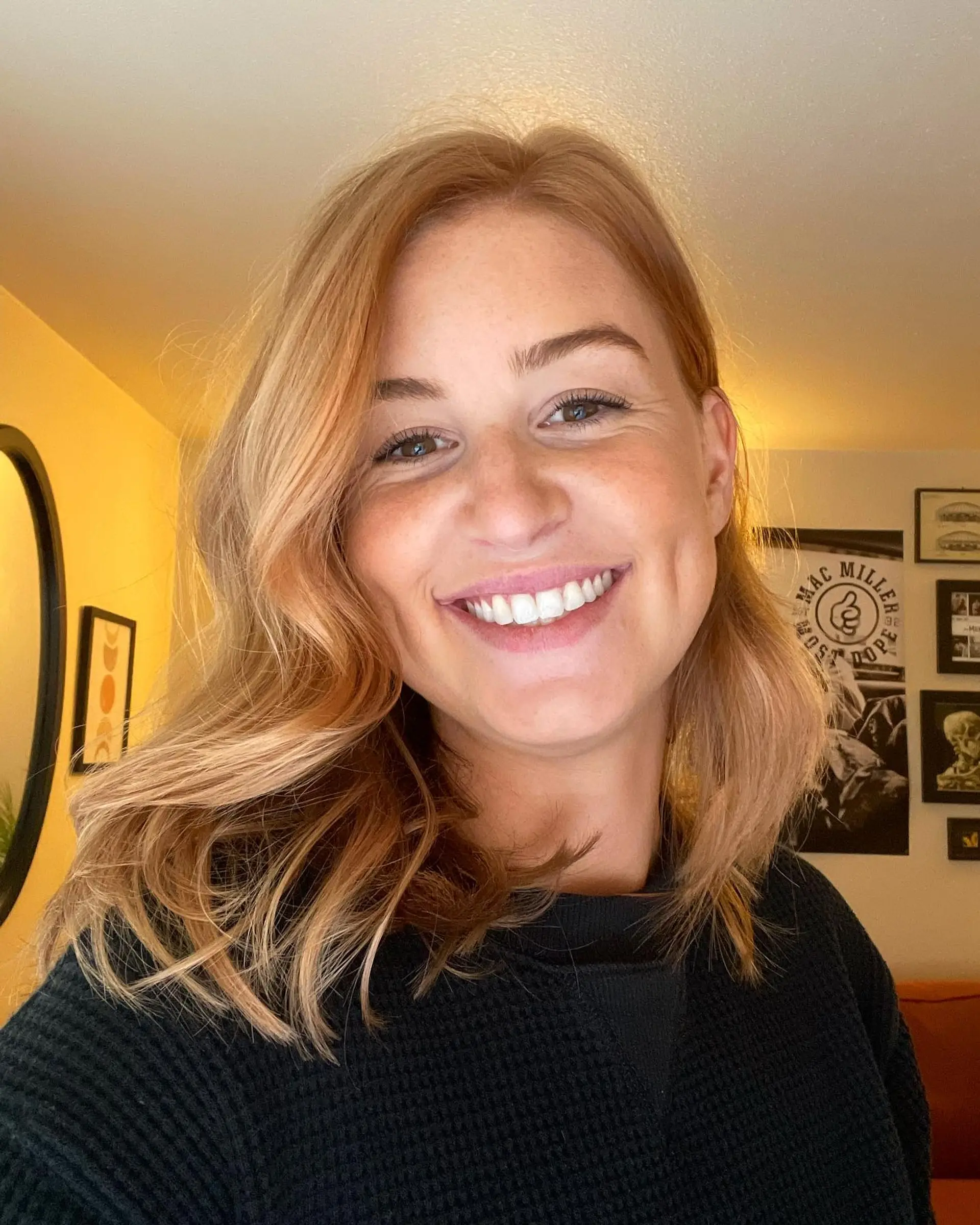 A medium-length cut styled in loose, soft waves with a warm strawberry blonde color. 1