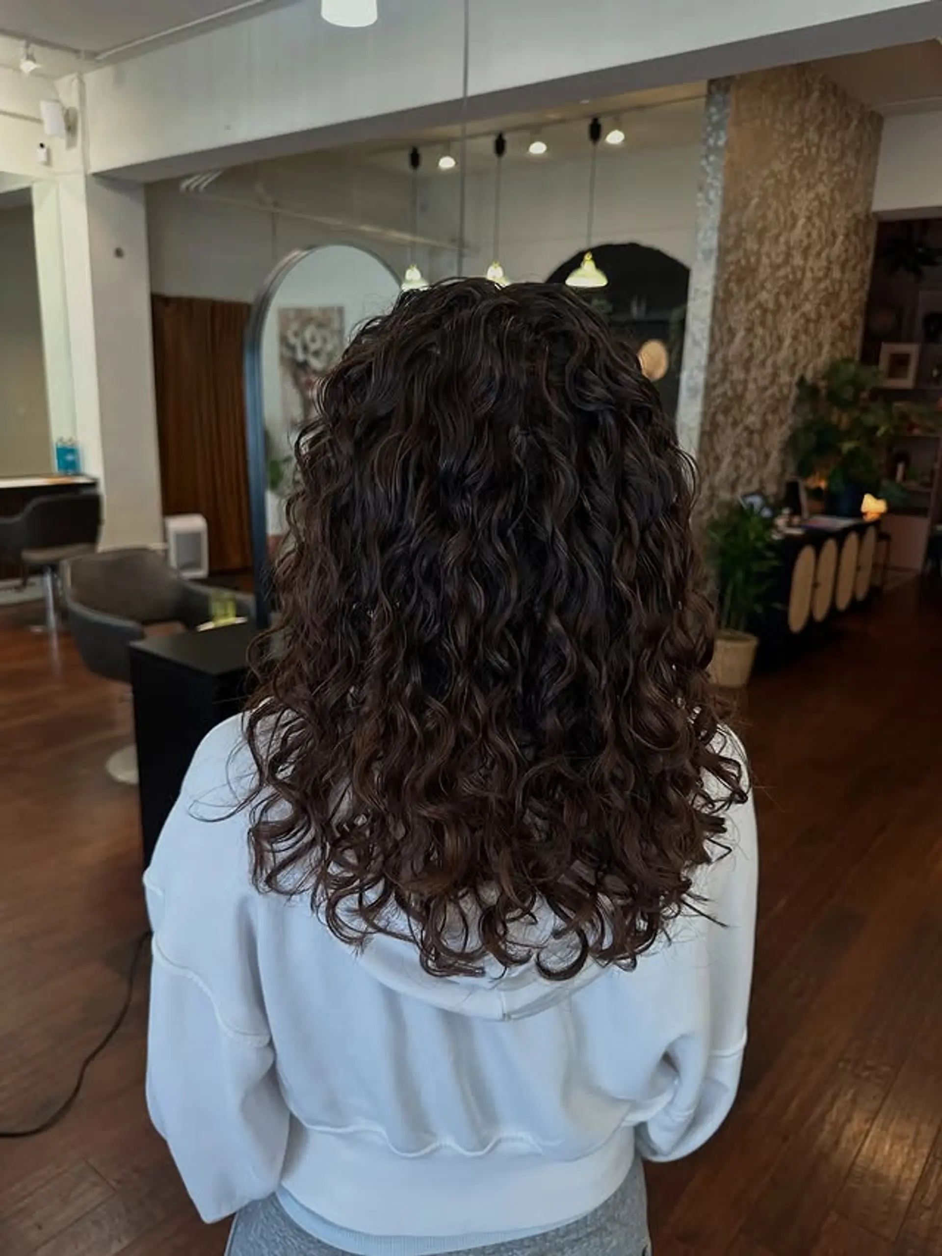 A medium-length, naturally curly hairstyle with well-defined curls and layers for added volume. 1