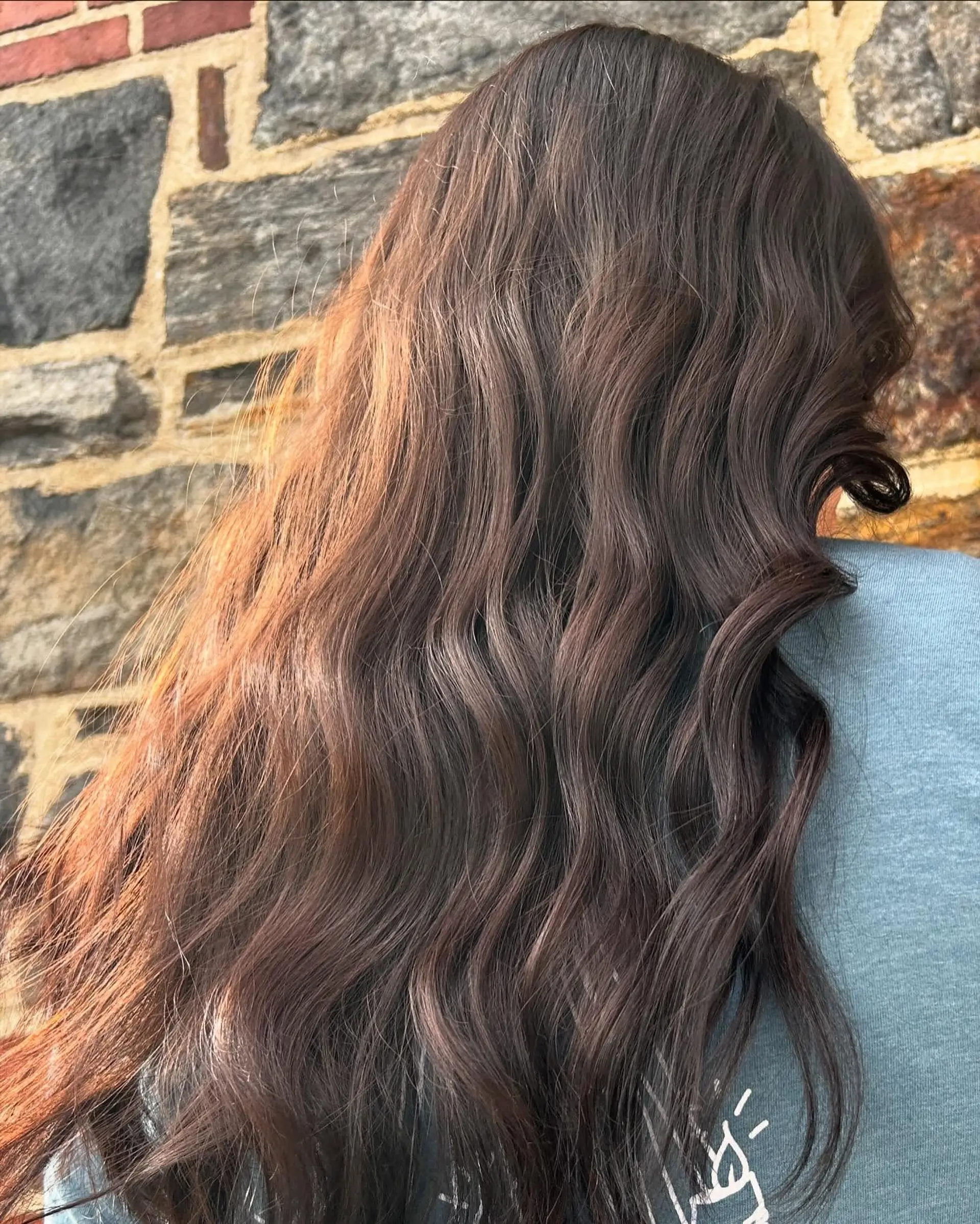 Rich, glossy dark brunette hair styled into loose, flowing waves. 1