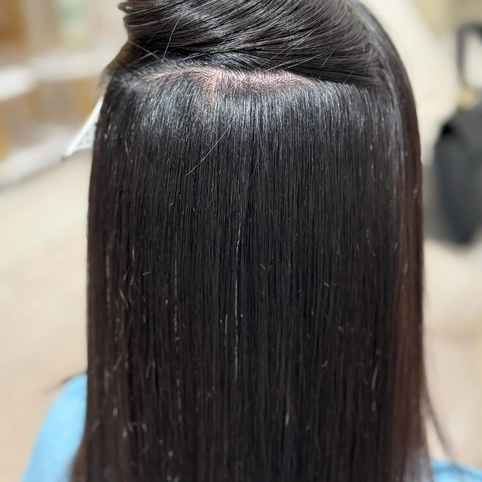 Medium-length, straight, black hair with a smooth, sleek texture and a light, glossy sheen. The parting at the top reveals a well-maintained, dense mane. 1