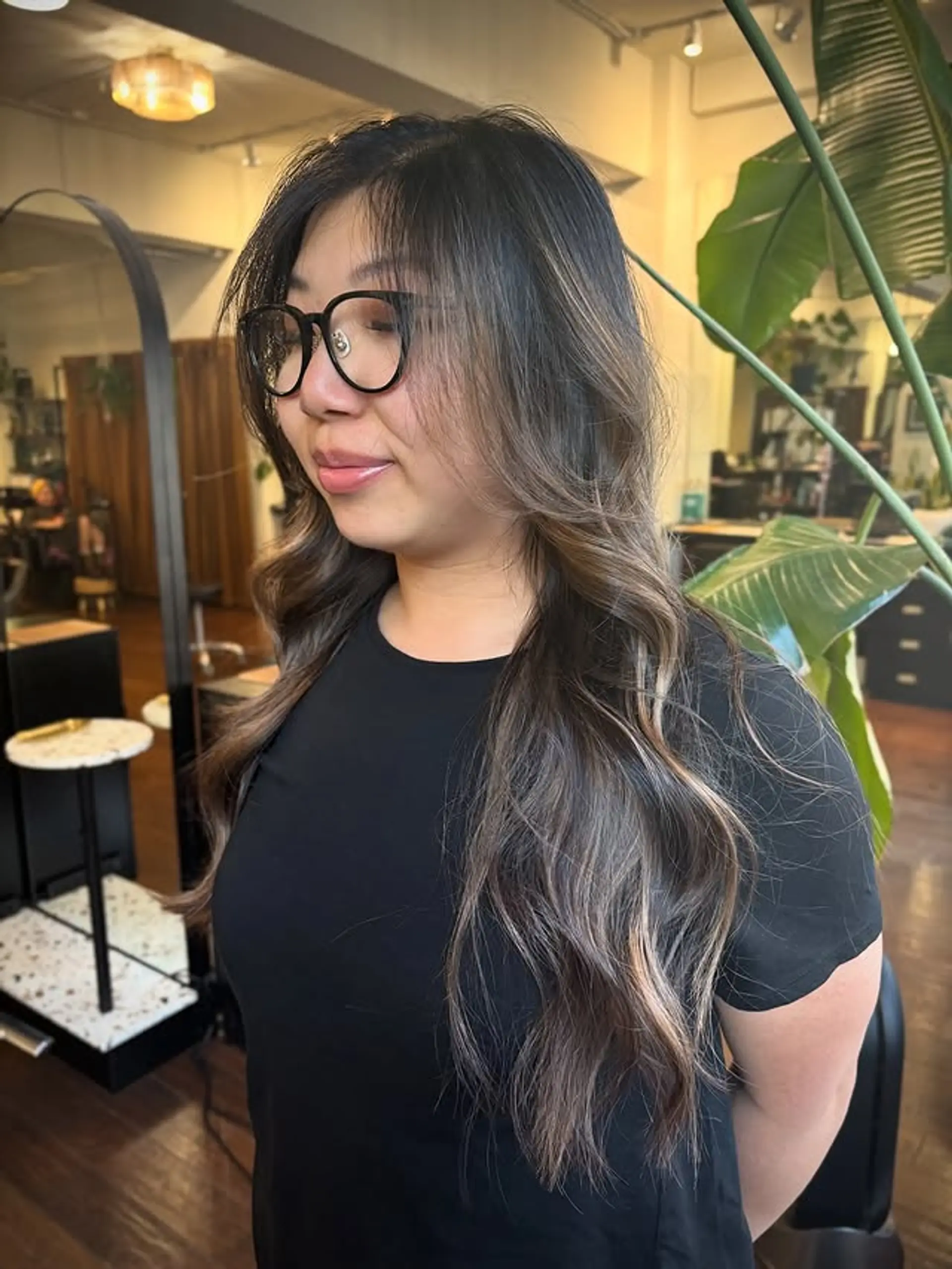 A long, wavy hairstyle with subtle blonde balayage and face-framing layers. 1
