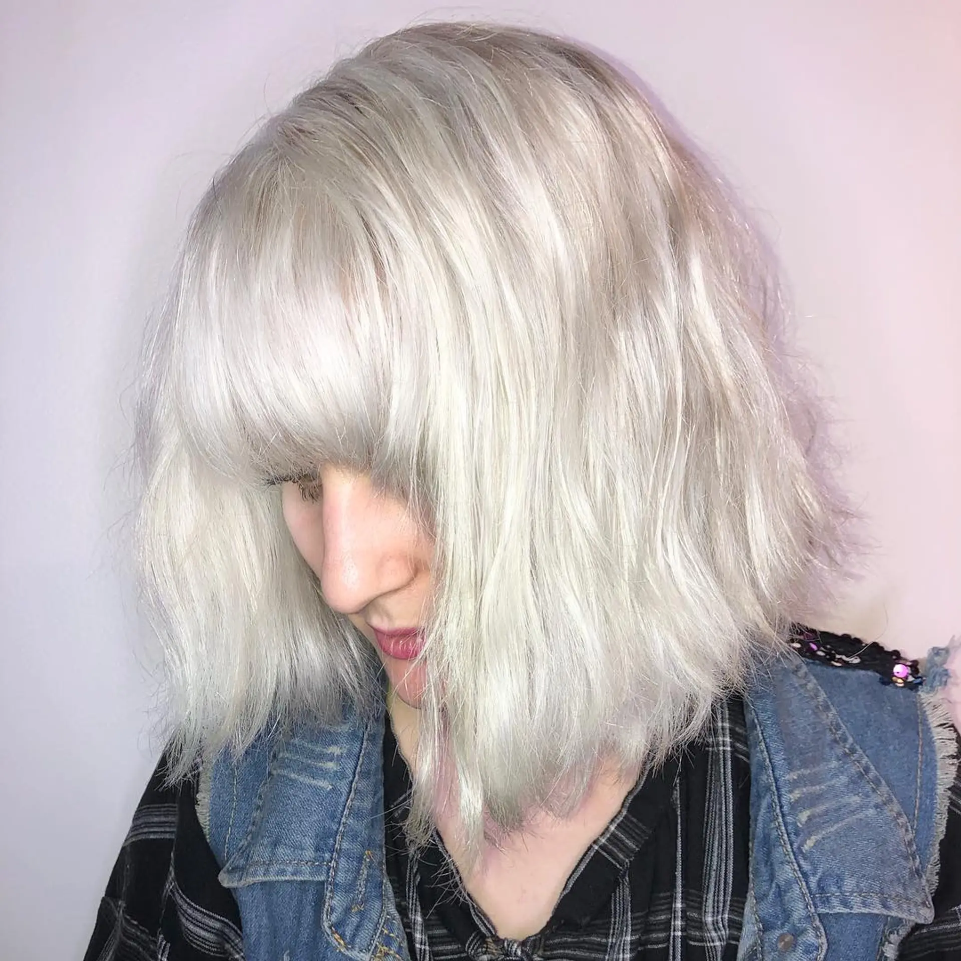 A bright platinum blonde lob with a textured, tousled finish paired with thick, blunt-cut fringe bangs. 1