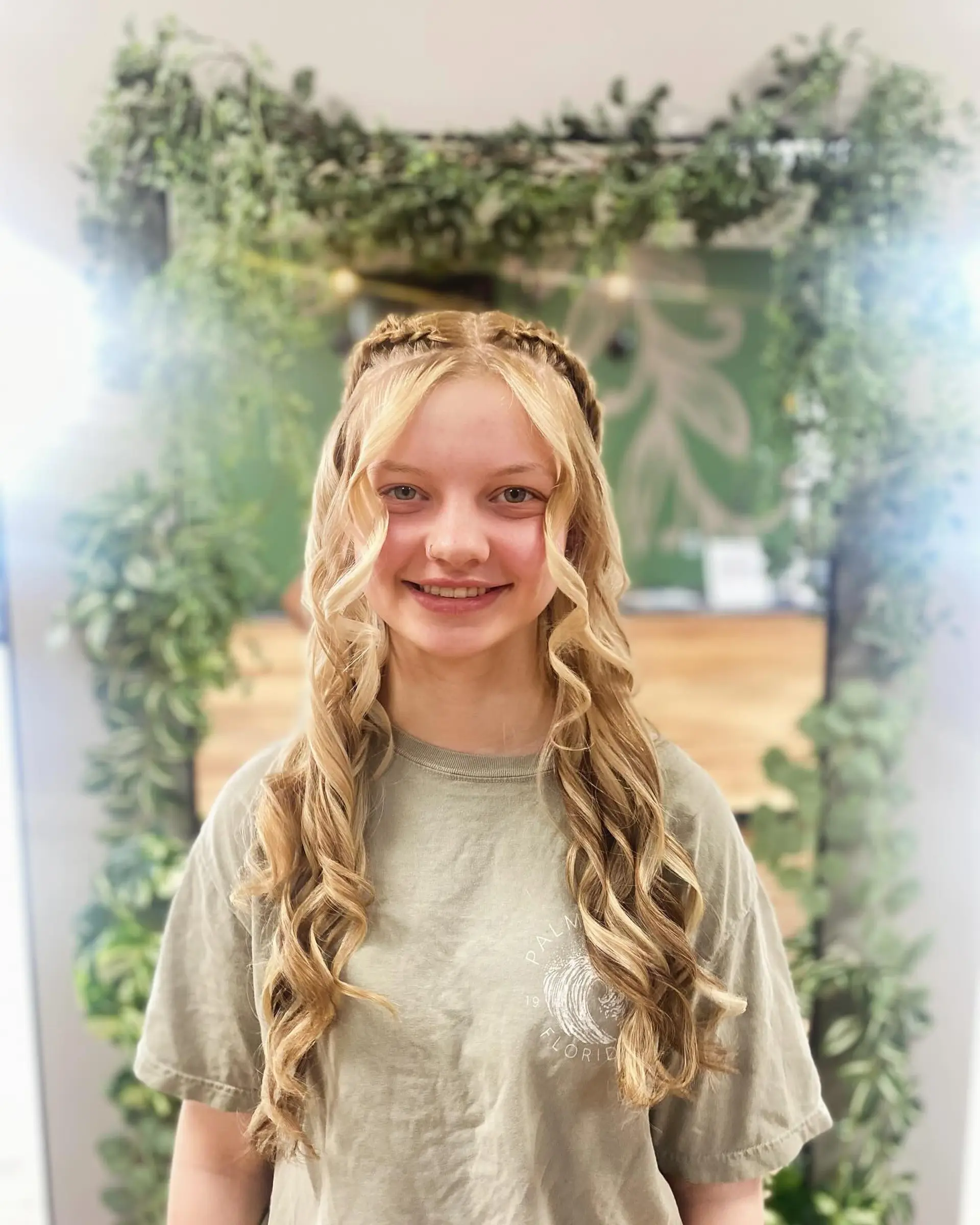 Long golden blonde hair styled with crown accent braids and defined, cascading spiral curls framing the face. 1