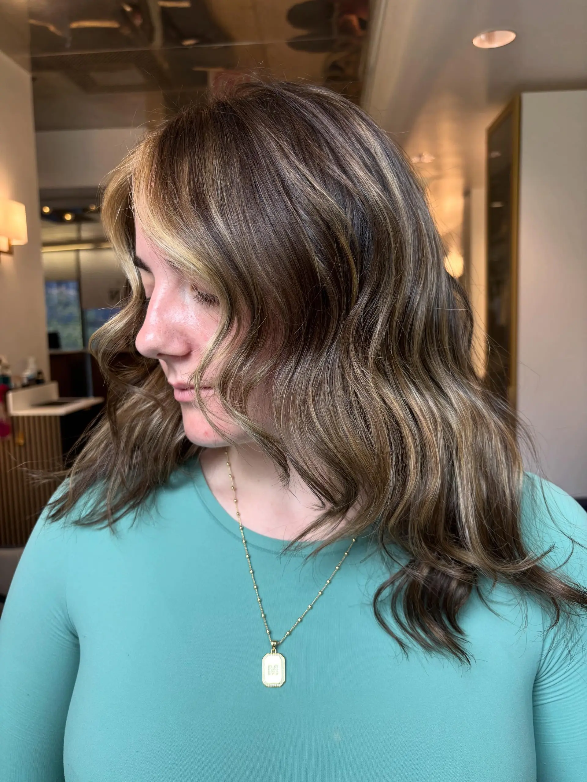 Medium-length dimensional brunette hair styled in loose, soft waves with subtle face-framing highlights. 1