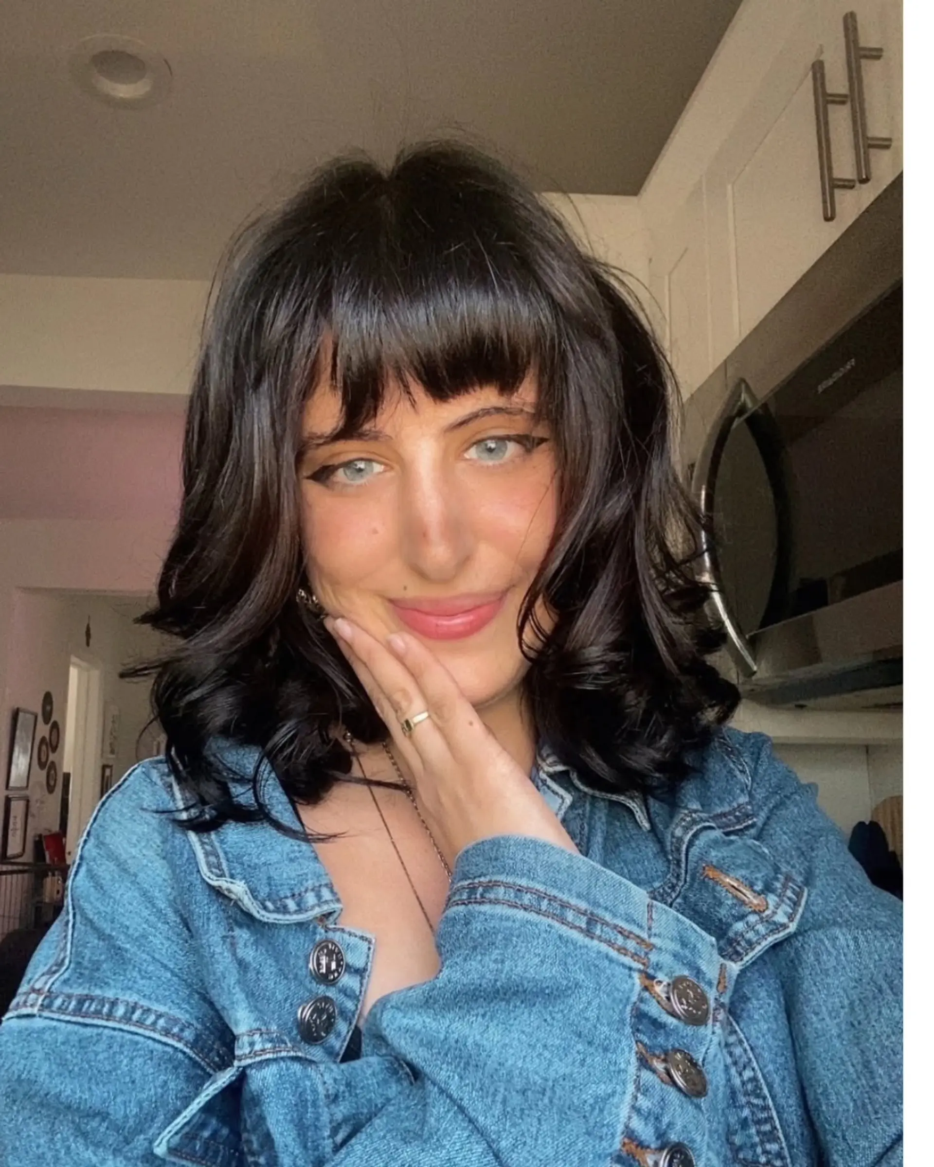 Shoulder-length dark hair styled into a textured shag with full bangs and soft, flipped curls at the ends. 1