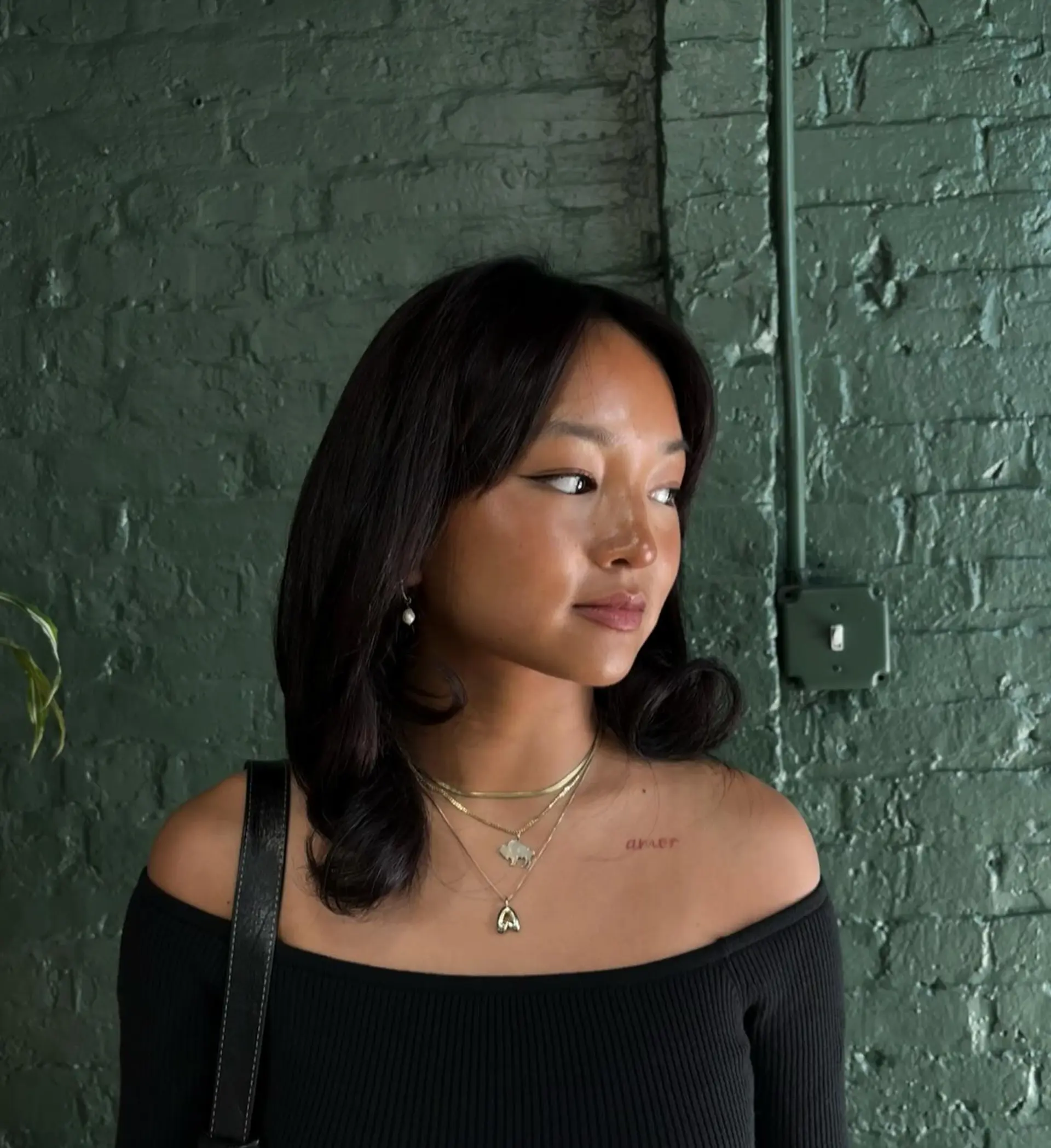 A glossy, dark mid-length cut styled with soft under-turned ends and gentle curtain bangs framing the face. 1