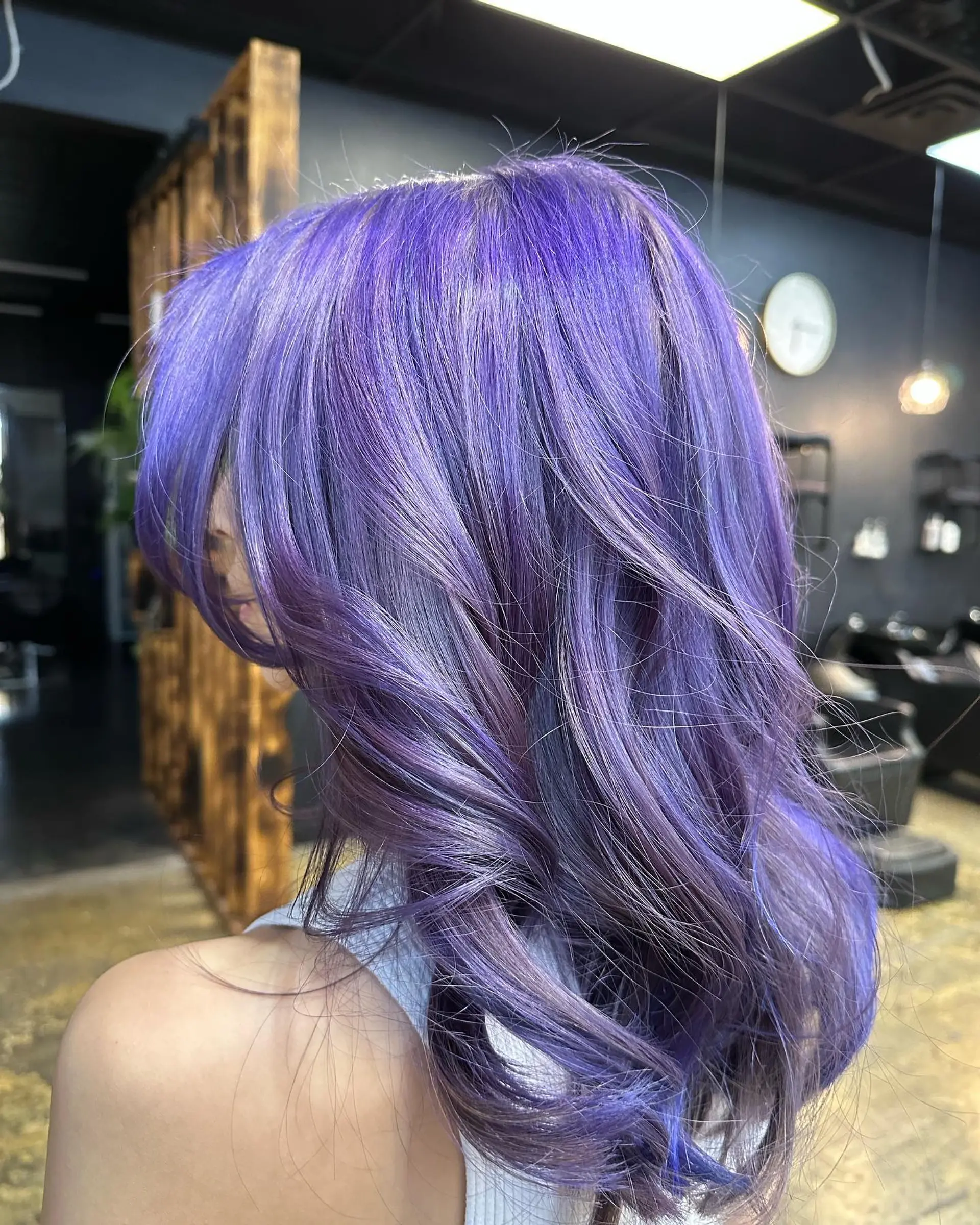 Long, layered, wavy hairstyle in vibrant purple and lavender colors, with side-swept bangs. 1