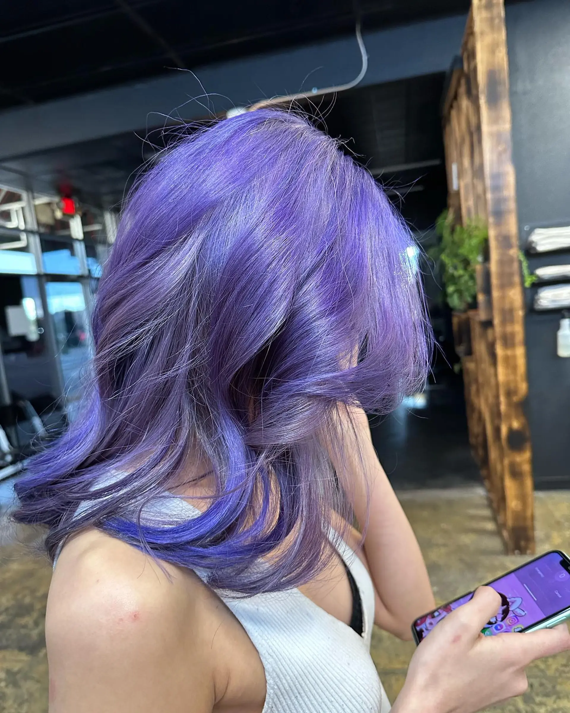 Long, layered, wavy hairstyle in vibrant purple and lavender colors, with side-swept bangs. 2