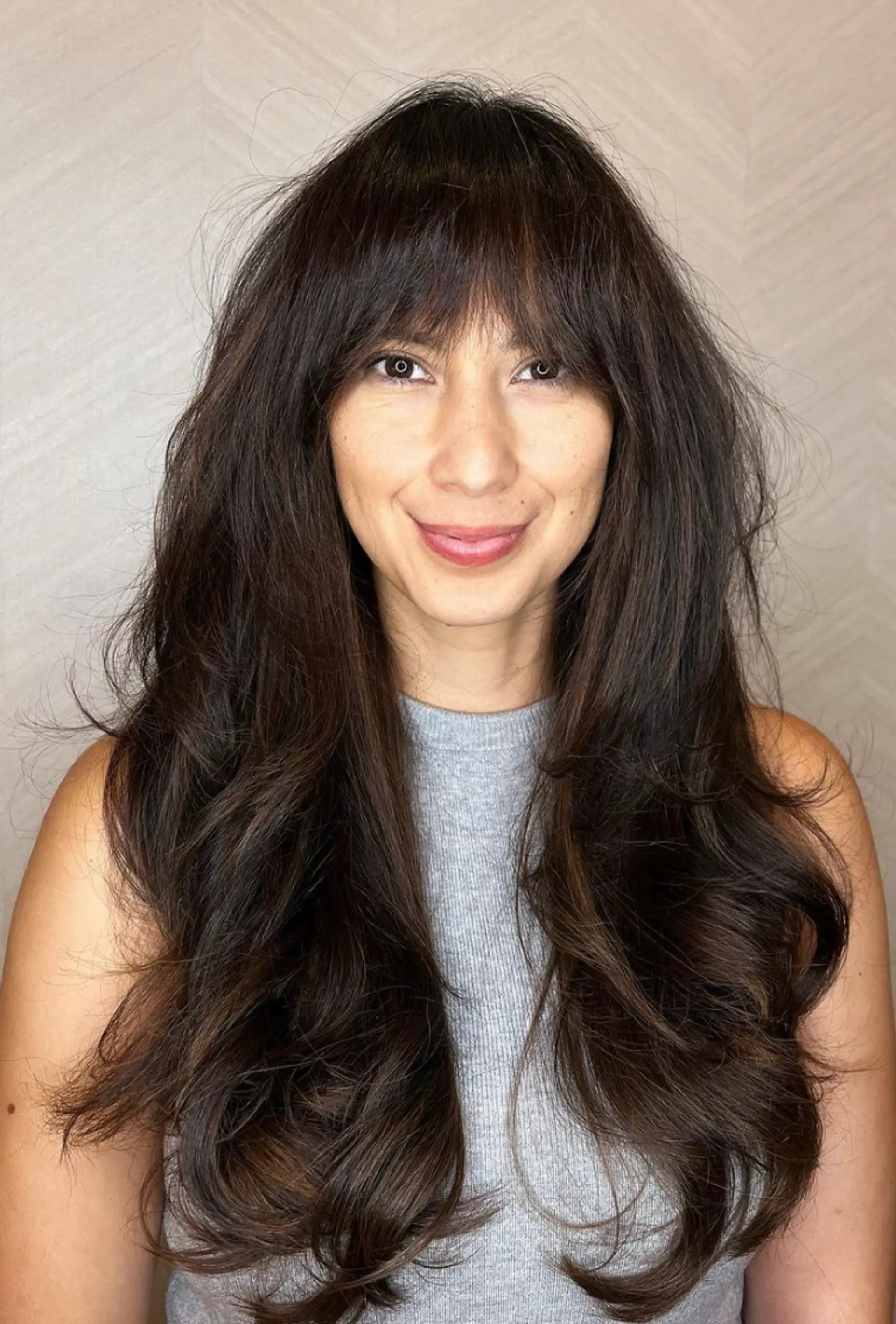 Very long, dark brown, heavily layered with natural waves and side-swept bangs, creating a voluminous and flowing hairstyle.

Cut and style by @juliamannino_hair
 1