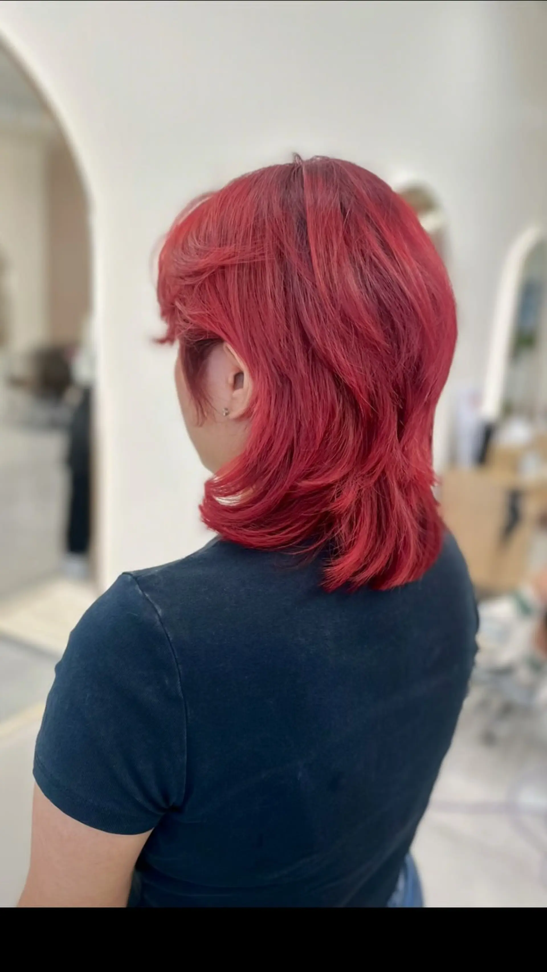 A medium-length textured mullet haircut featuring feathered layers and dyed in a vibrant cherry red. 1