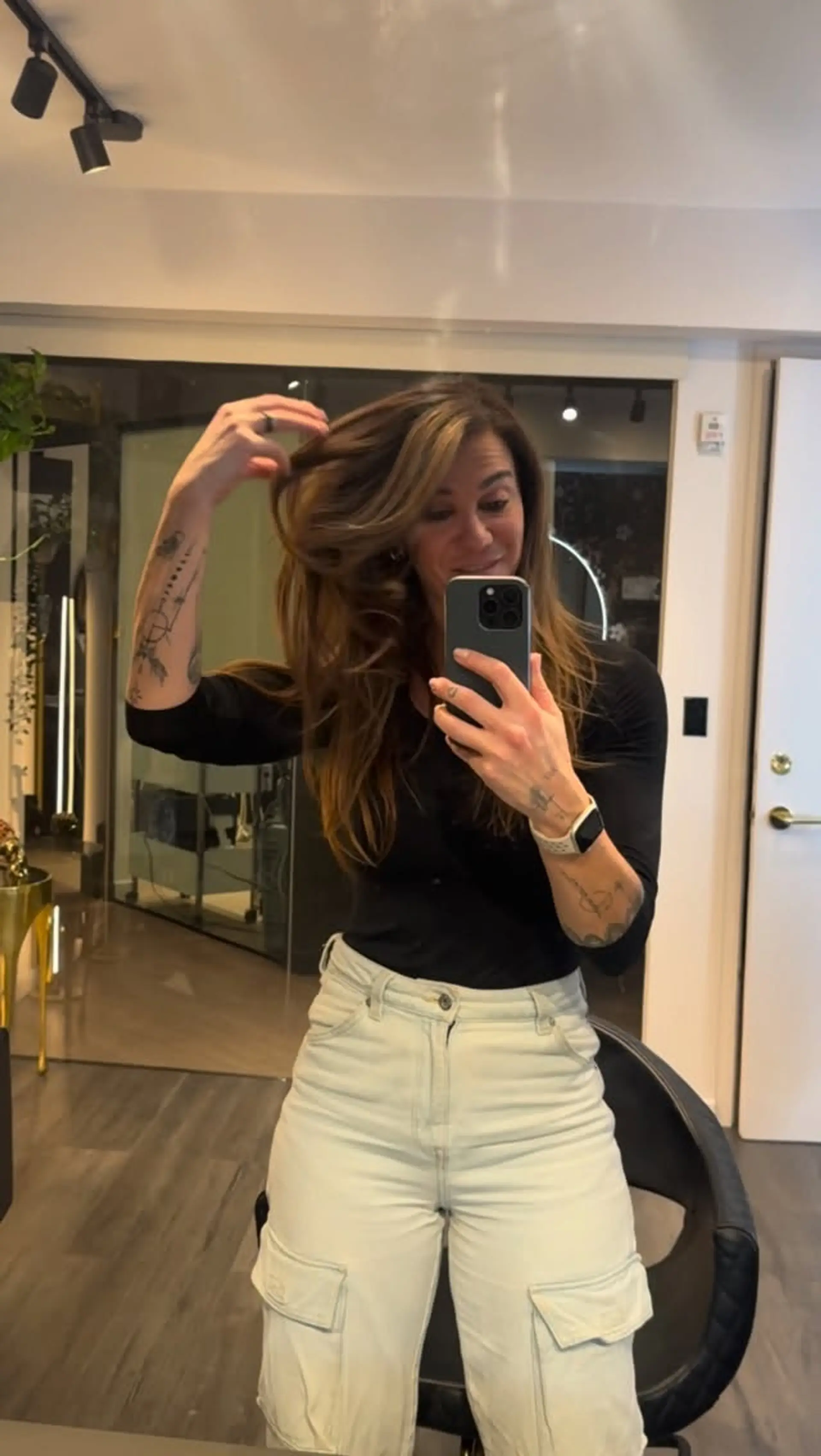 Long layered warm brunette hair styled into a voluminous, bouncy blowout with face-framing lighter strands. 1