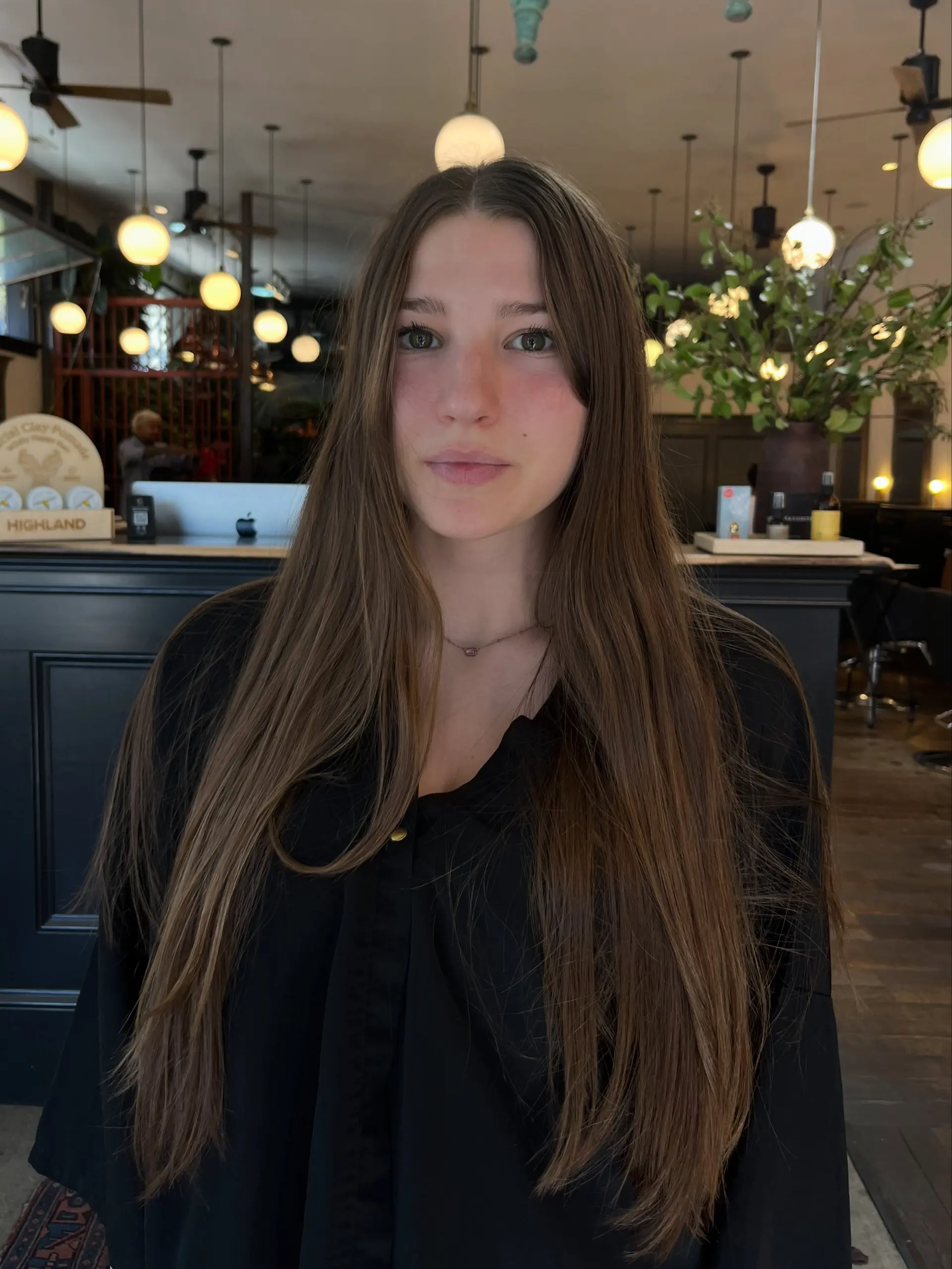 Long brunette hair styled straight with a center part and soft, warm golden highlights throughout. 1