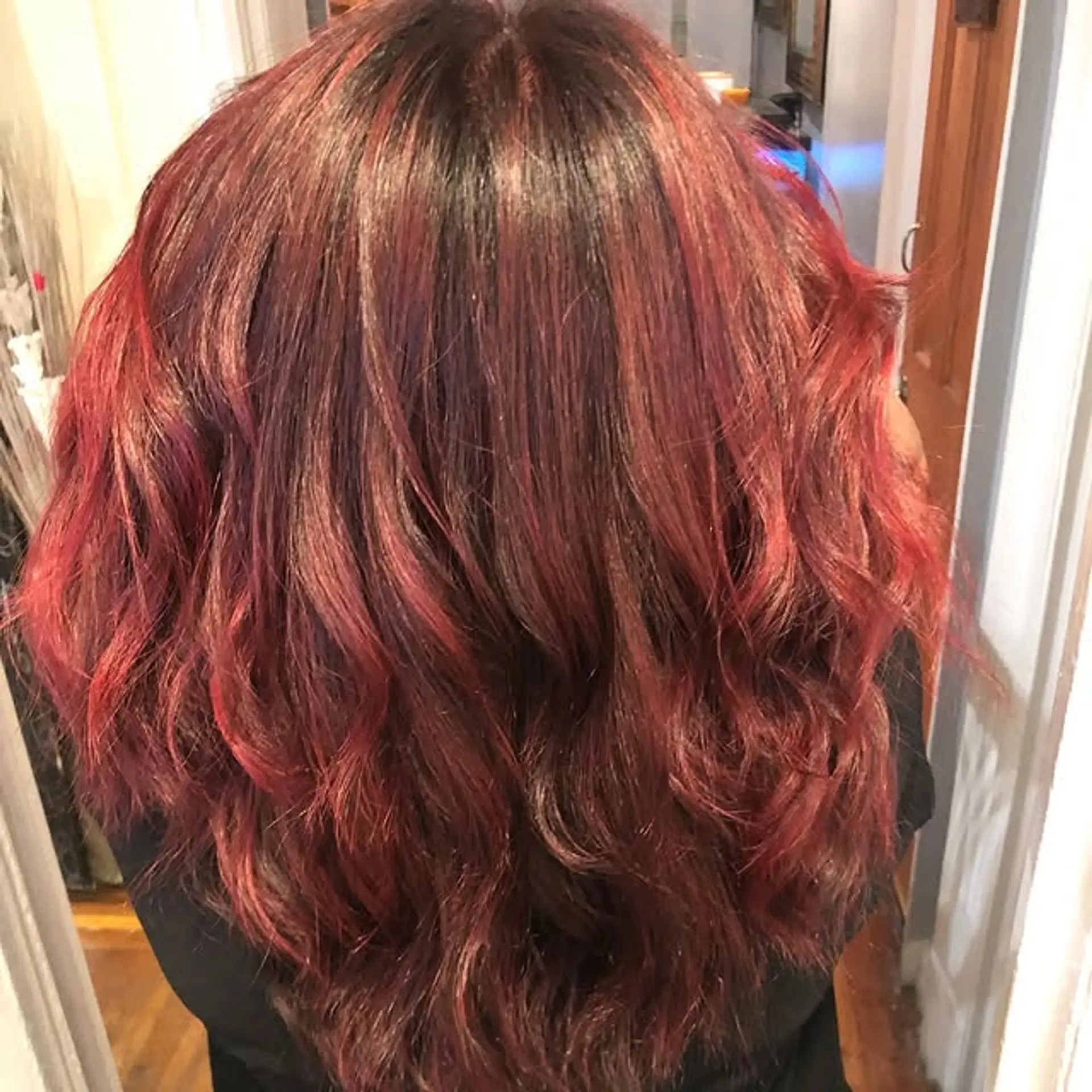 Long, wavy hairstyle with a red balayage and dark roots. 1
