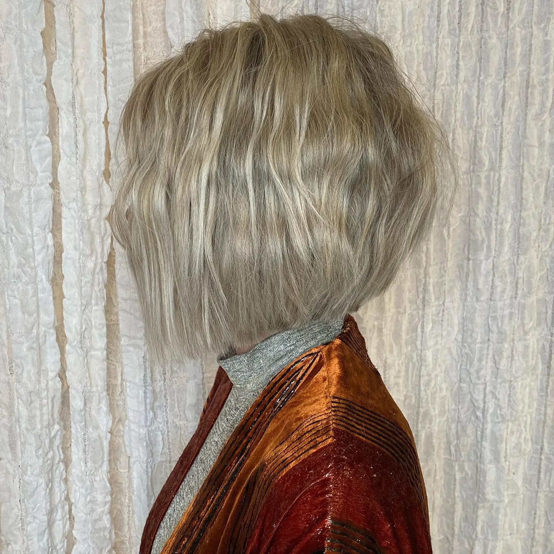 A textured chin-length bob in a cool, icy ash blonde tone with tousled styling. 1