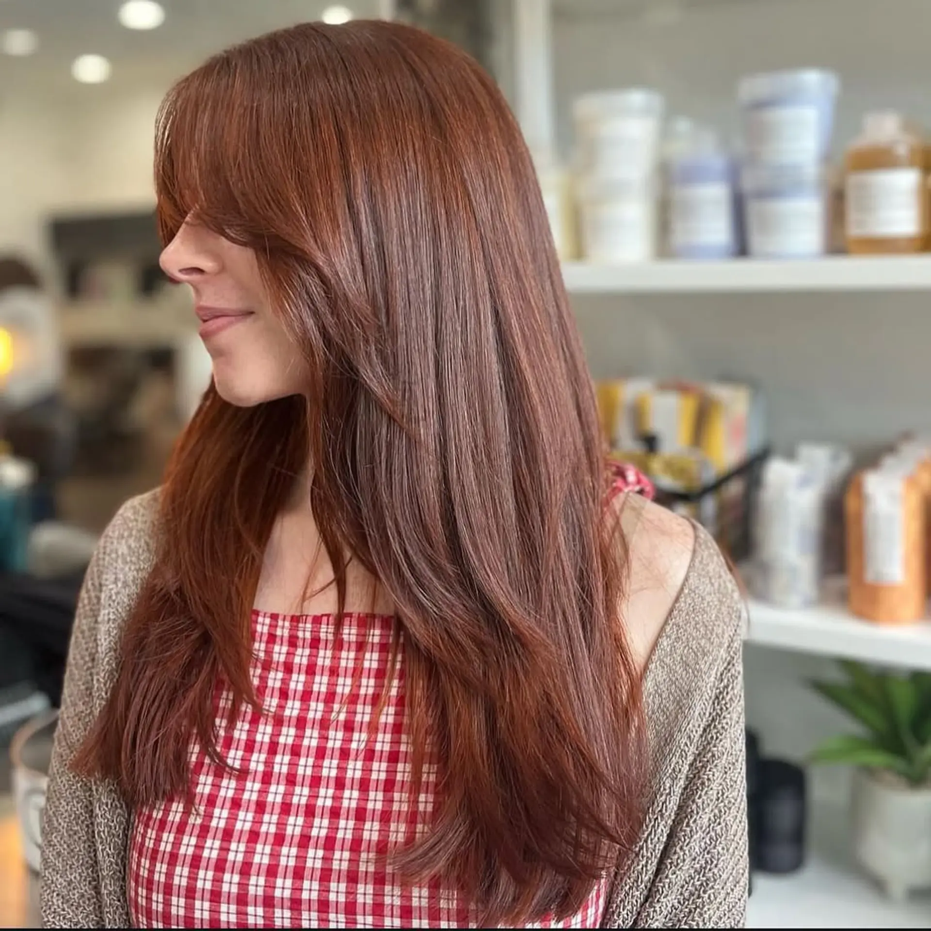 Long, straight hair with subtle layers for movement and face-framing curtain bangs. The ends have a slight inward curl, adding softness to the overall look. 1