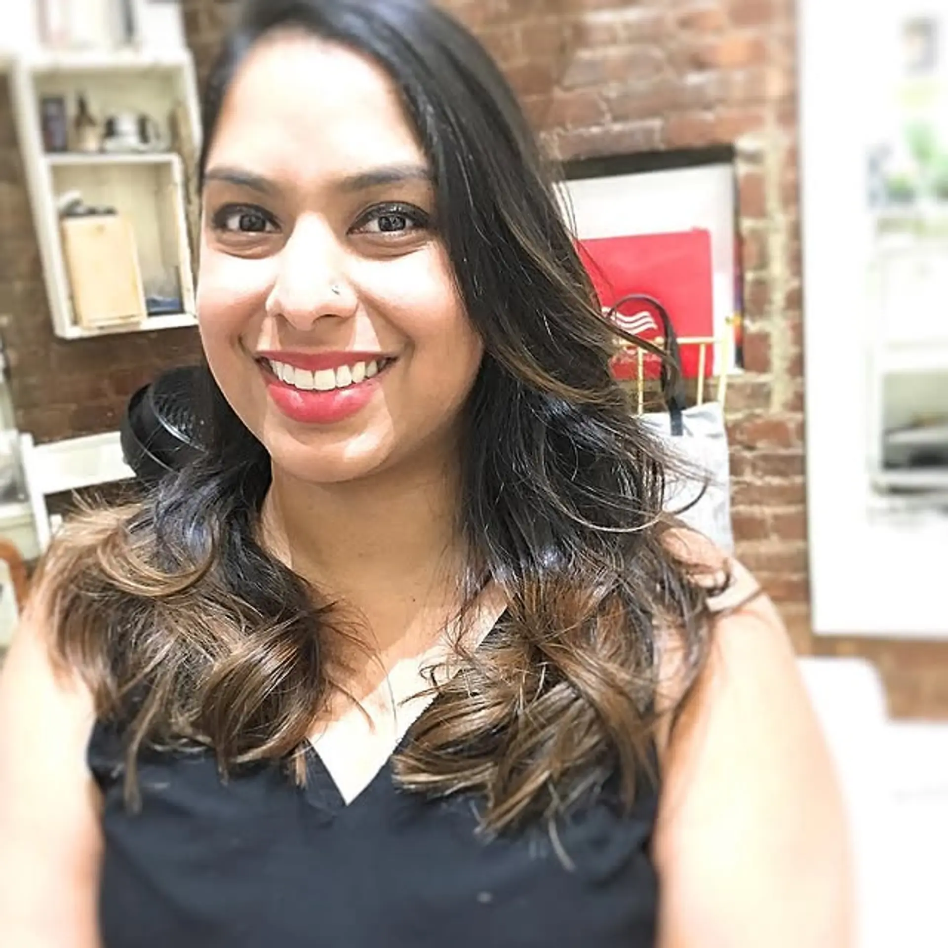 Long, layered hair with dark roots fading into a bronde balayage. 1