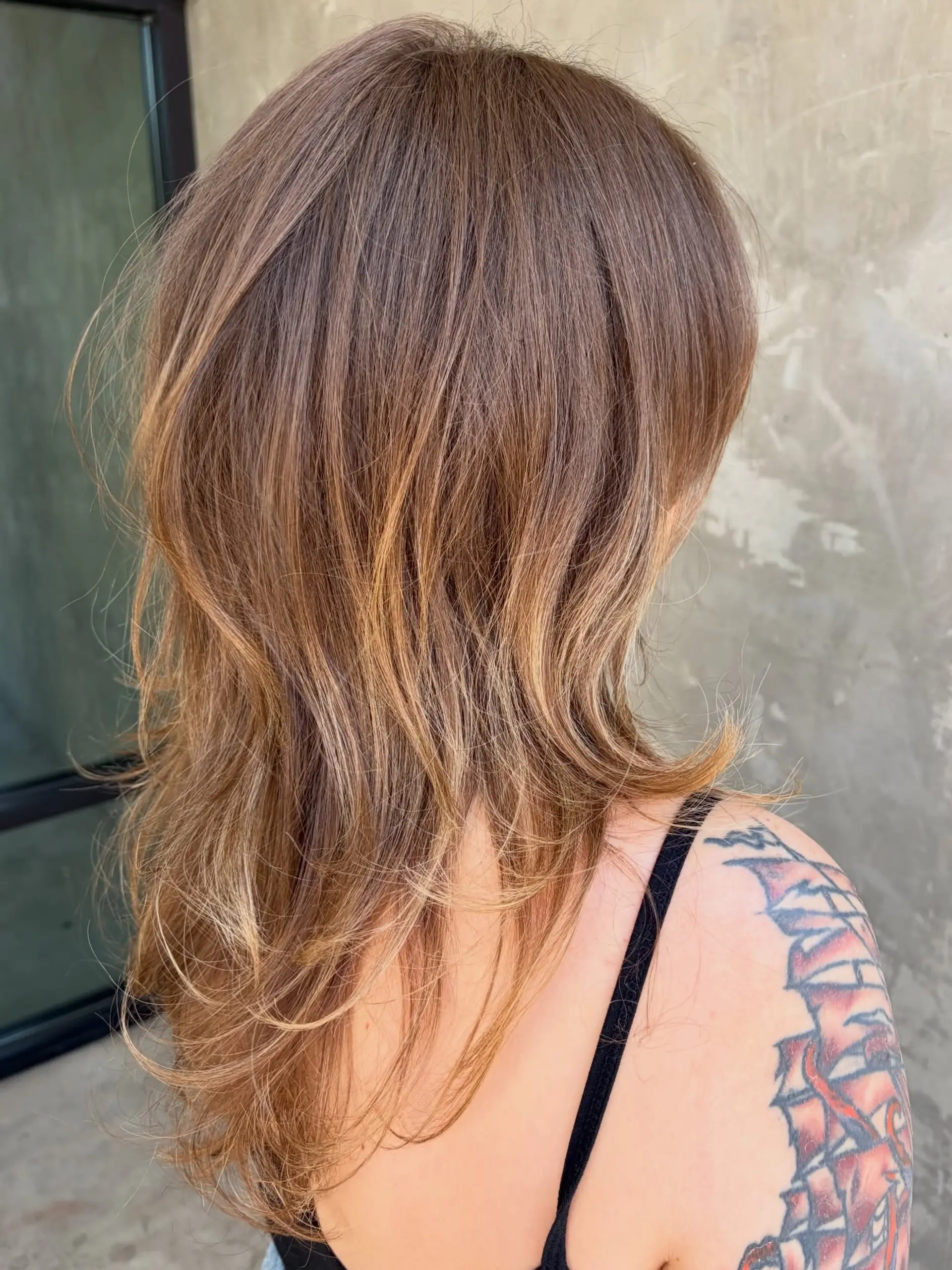 A textured long-layered haircut featuring soft feathered layers and flipped-out ends with warm dimensional highlights. 1