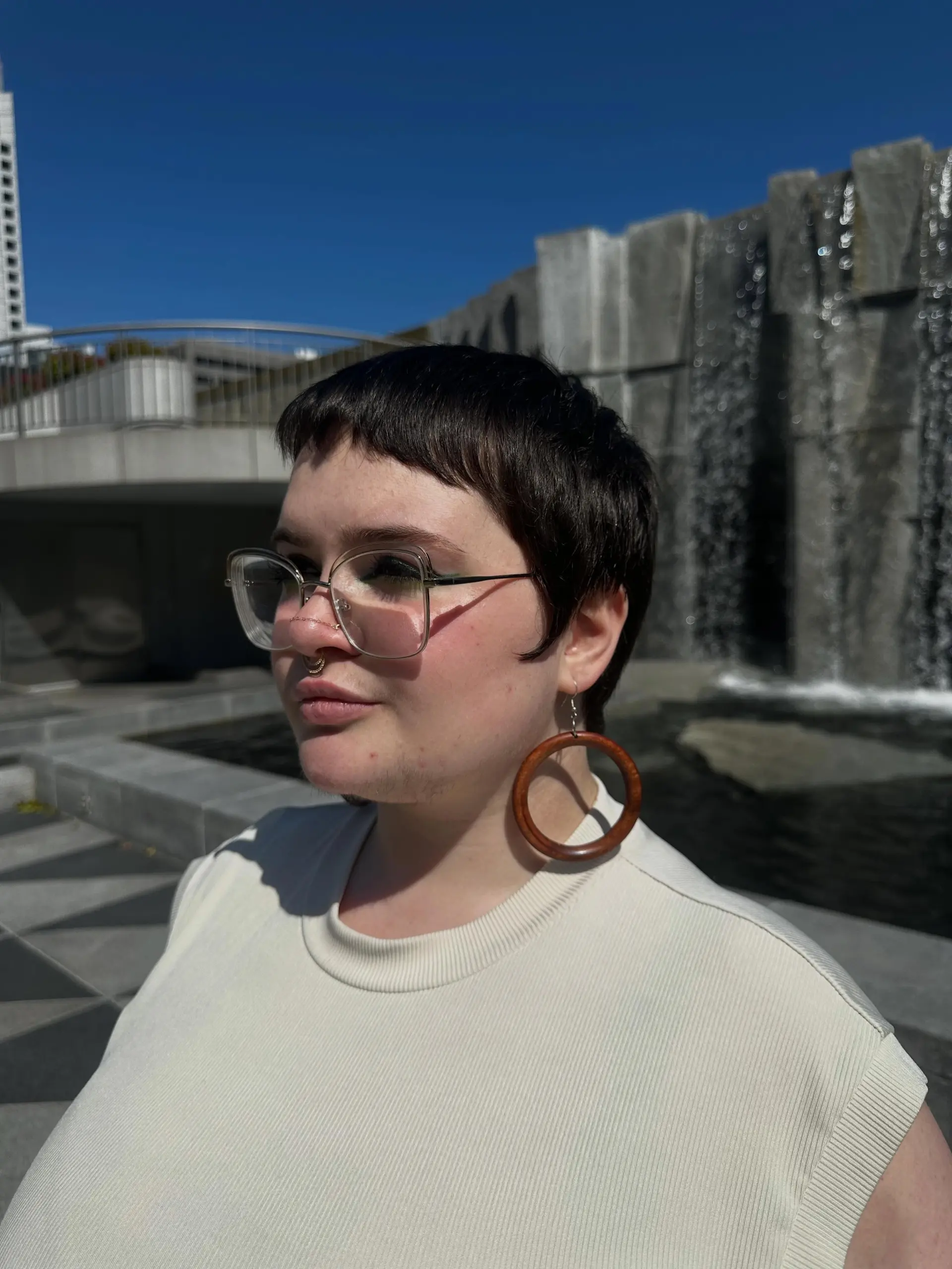 A textured short pixie crop in natural dark brown featuring soft micro bangs. 1