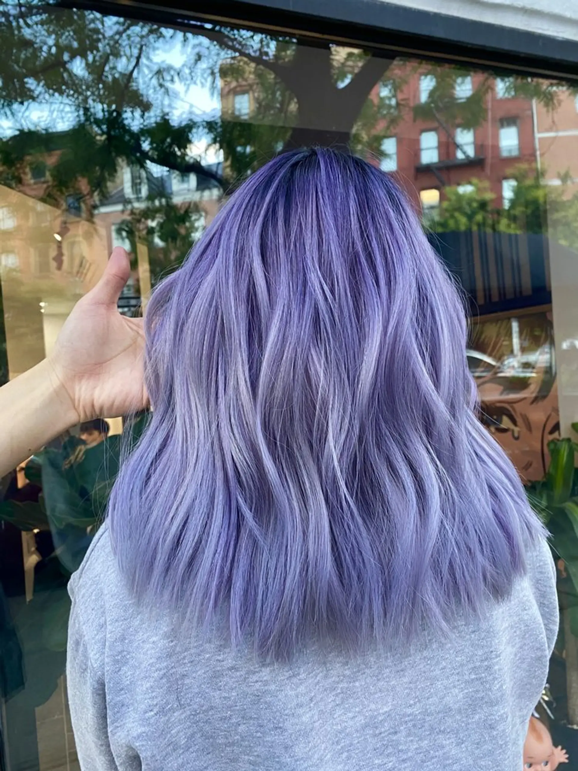 A beautiful and vibrant medium-length wavy hairstyle in a striking shade of light purple with lavender tones, giving it a bold and trendy look. Soft and natural waves add volume and movement to the hair. 1