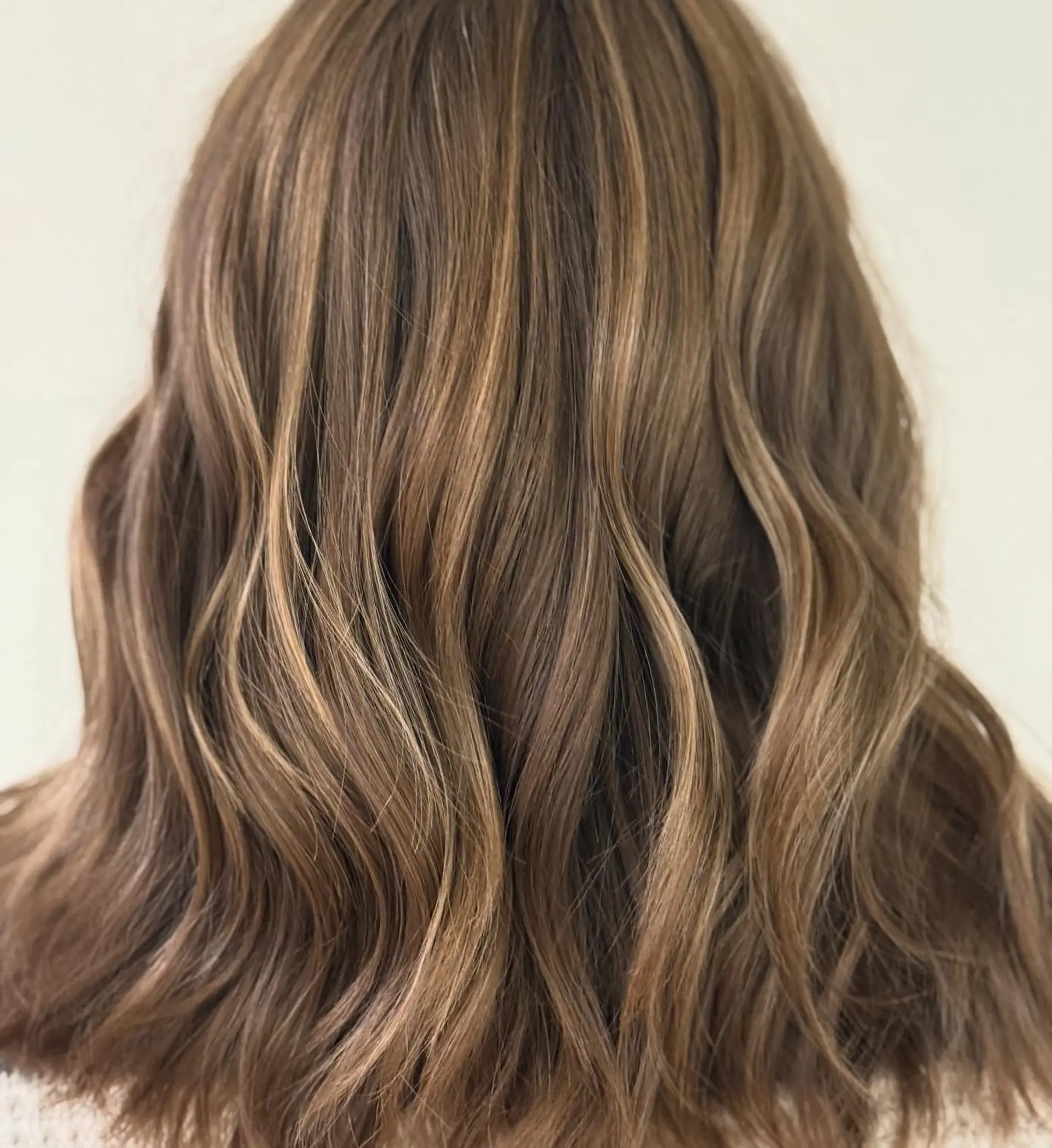 Medium-length light brown hair styled in relaxed waves with honey highlights. 1