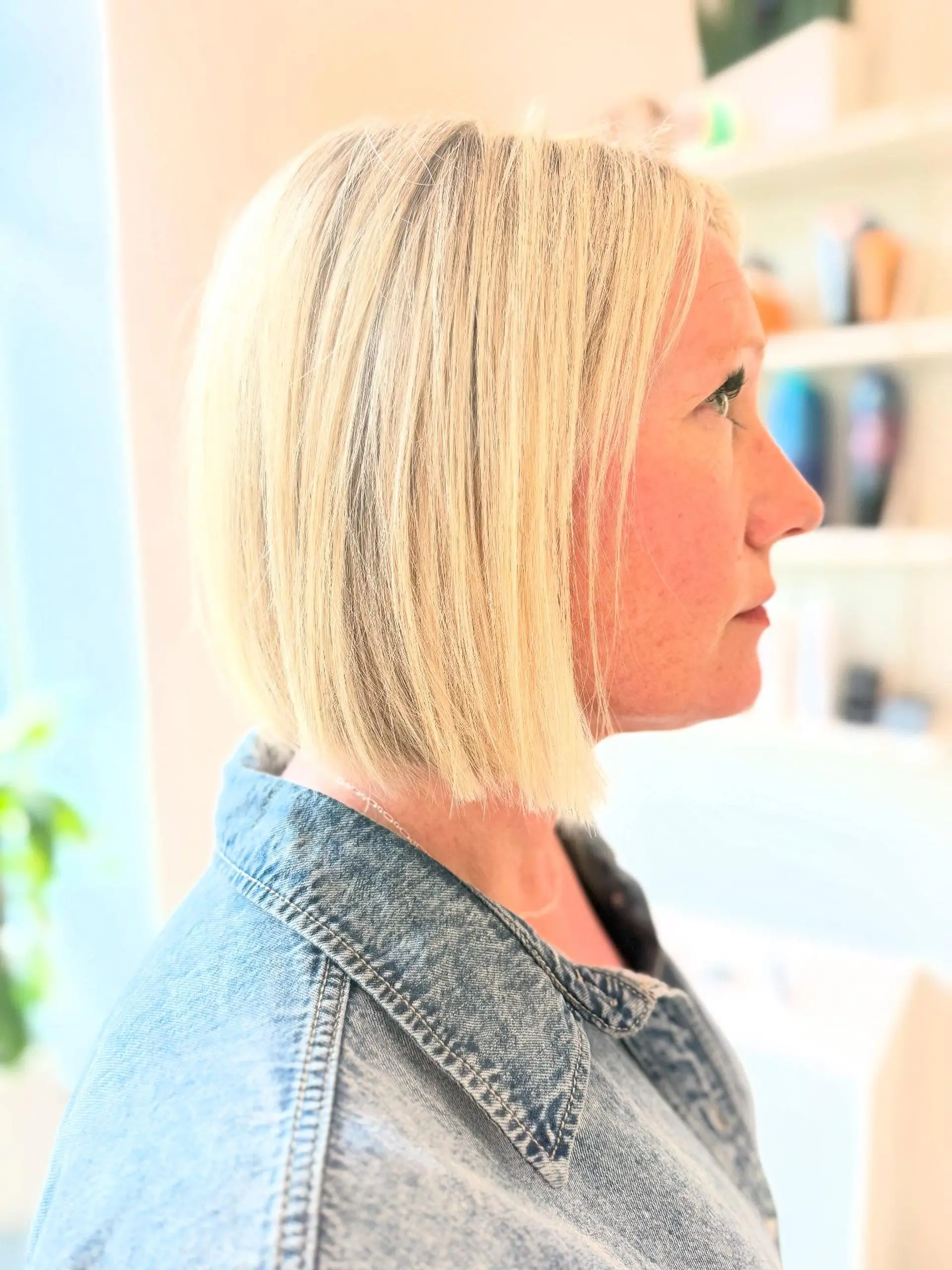 A sleek, chin-to-neck length blunt bob cut straight across with bright blonde highlighting. 1