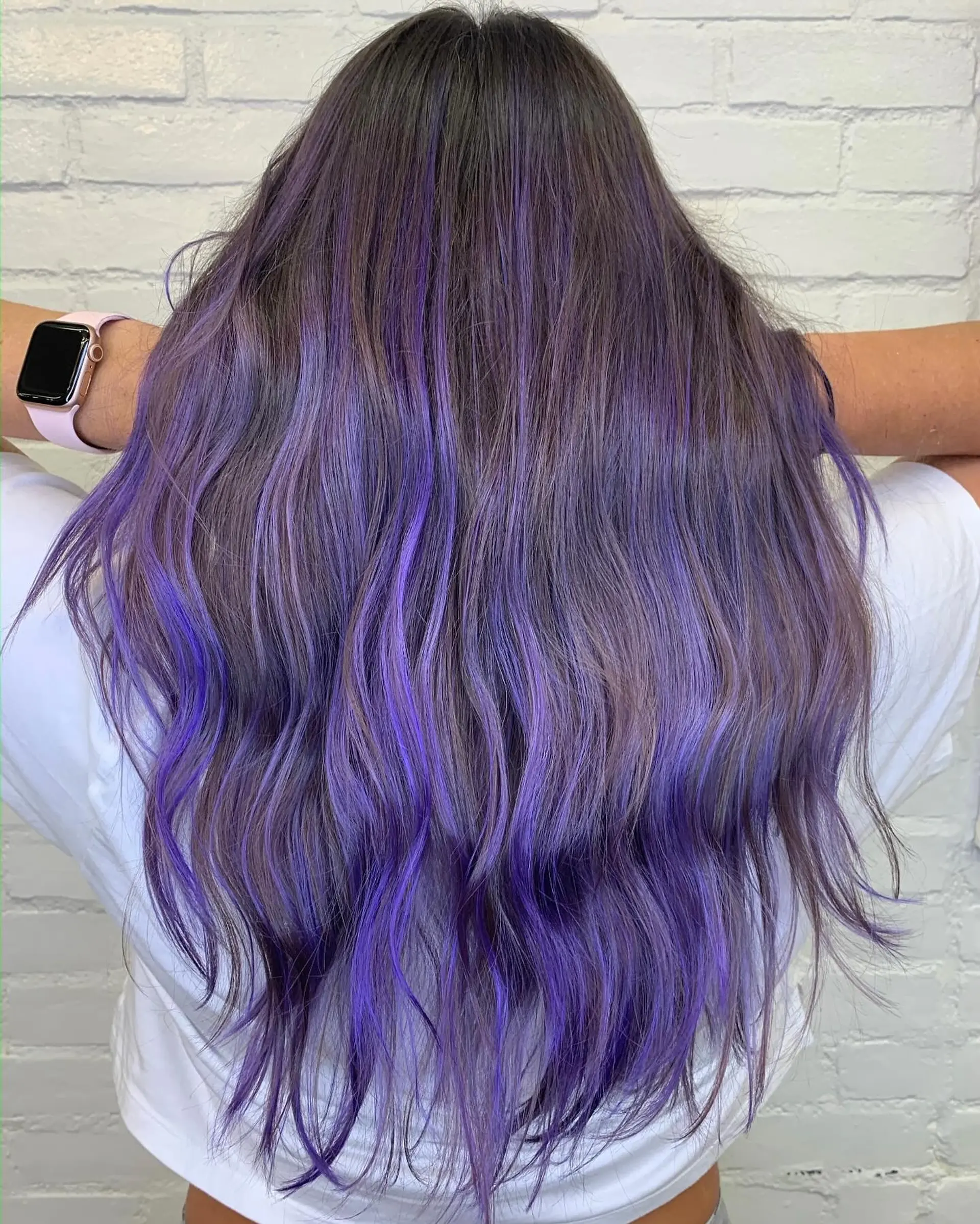 Long, tousled dark hair featuring vibrant purple and violet highlights woven throughout. 1